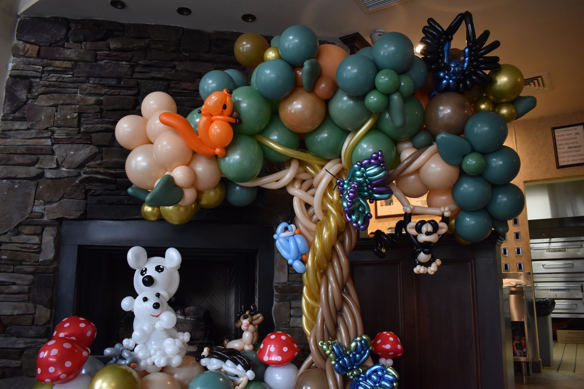 Balloon forest scene with tree, animals, and mushrooms on a fireplace mantel.
