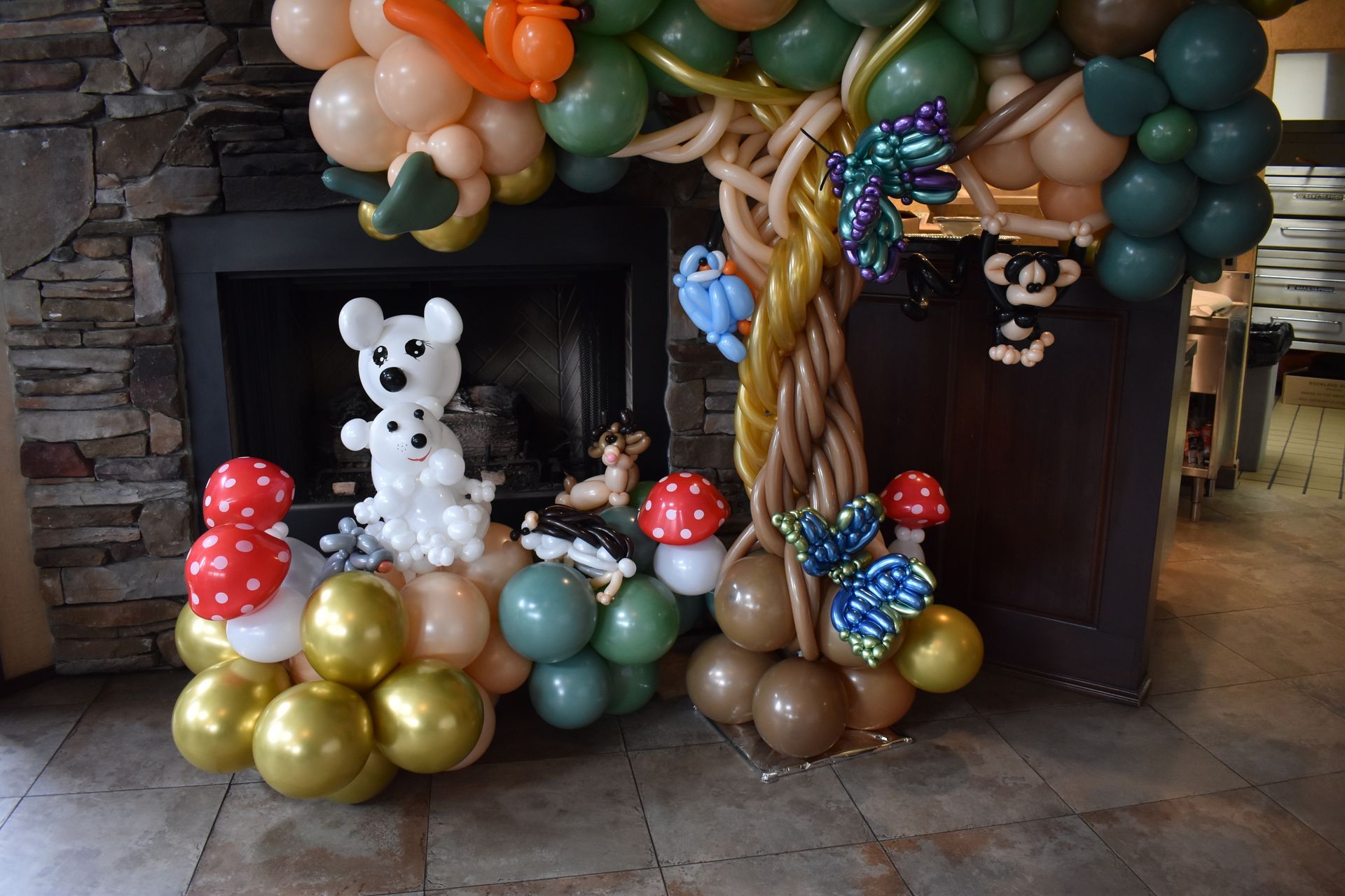Balloon animal display: tree with animal figures in front of a fireplace.