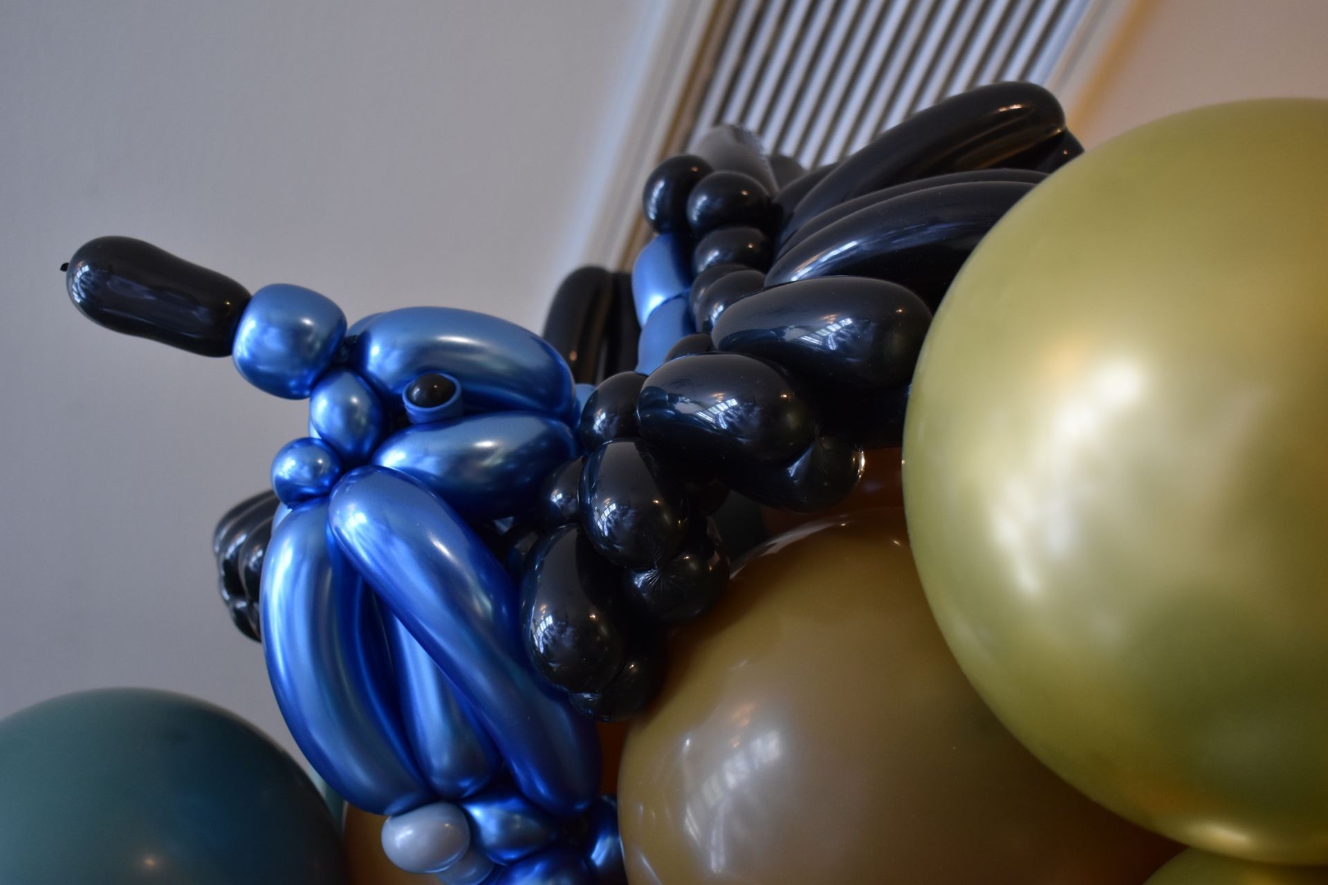 Close-up of a balloon sculpture with blue, black, gold, and brown balloons.
