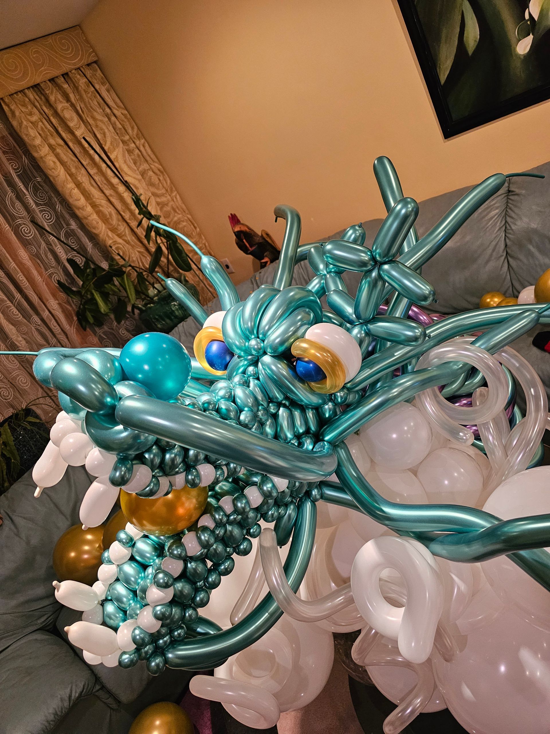 Blue balloon dragon sculpture with white and gold accents; indoors.