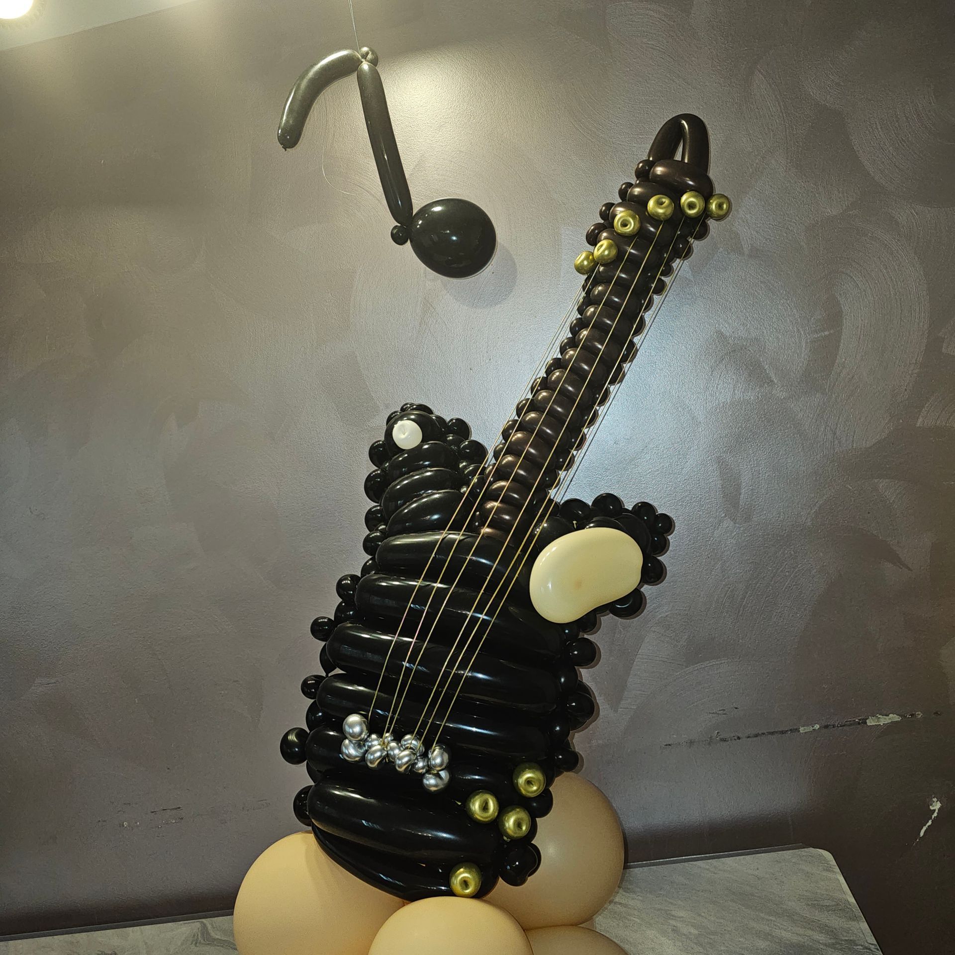 Black balloon guitar with gold accents and a musical note made of balloons.