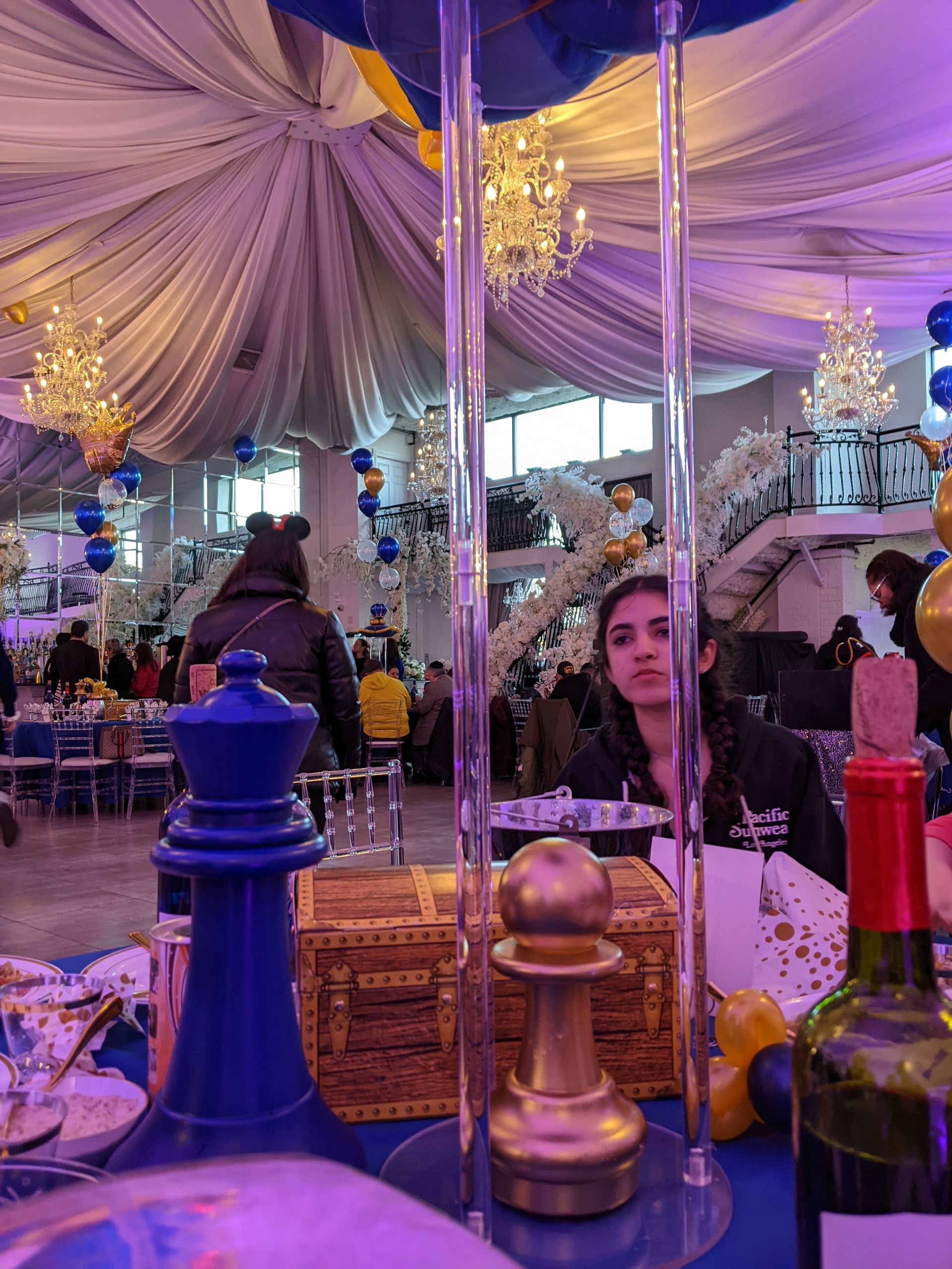 Party scene with tables, decor in blue and gold; a person looks at the camera.