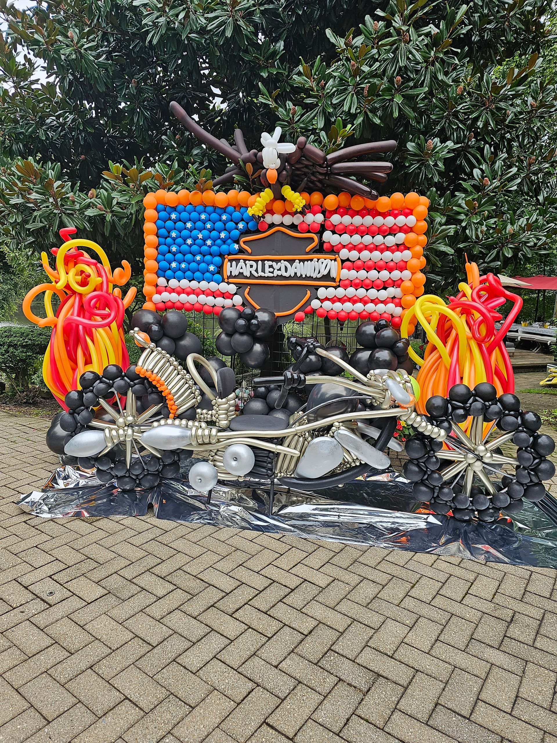 Balloon sculpture of a Harley Davidson motorcycle with an American flag background and flames.