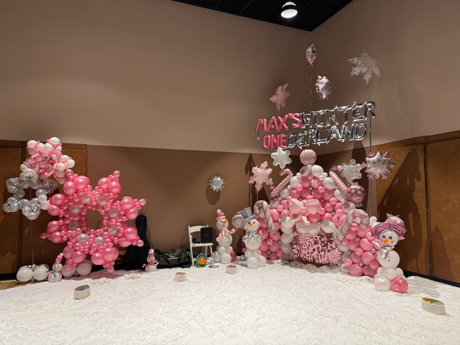 Pink and white balloon winter wonderland party decorations with snowflake and snowman features.