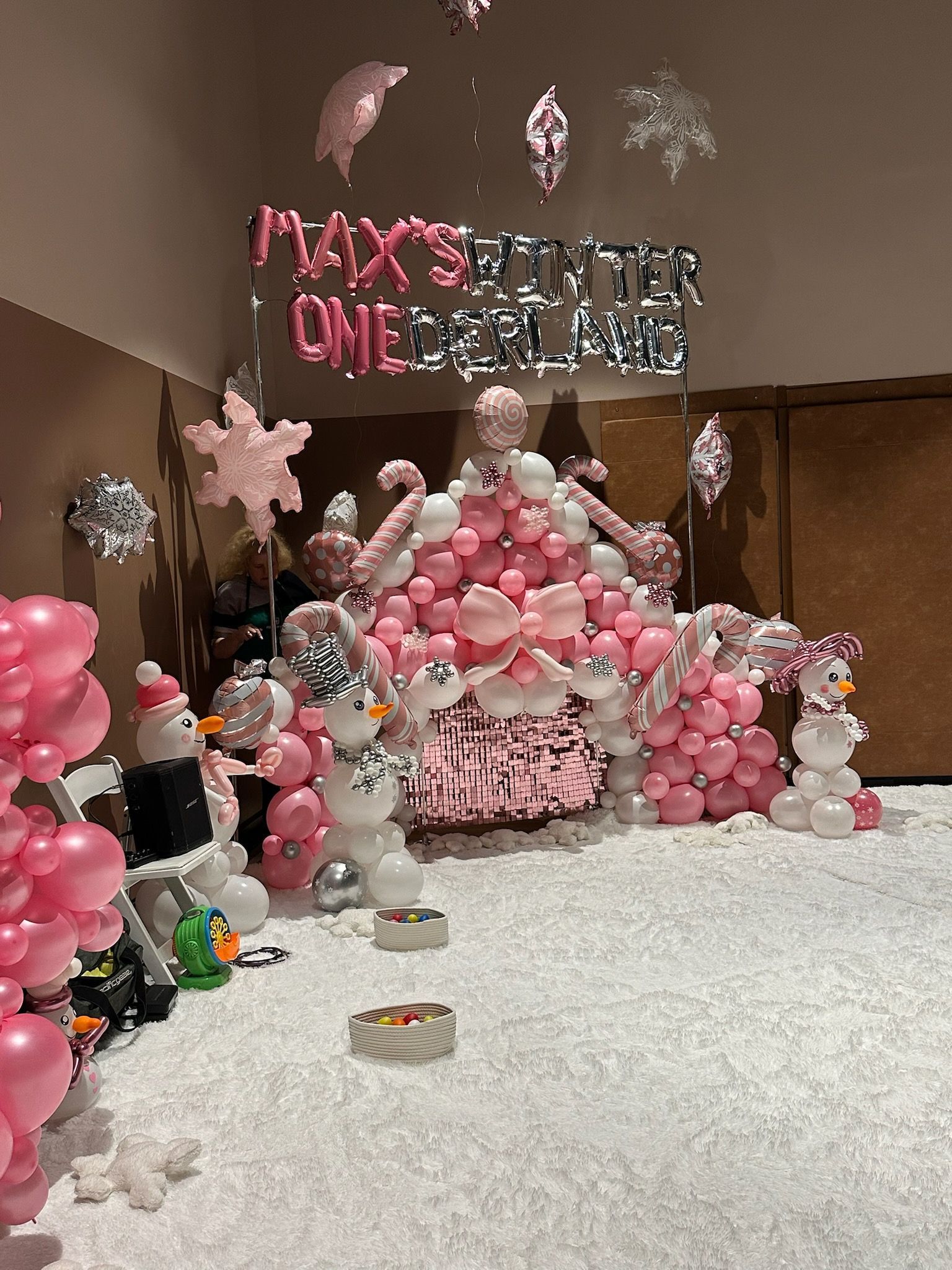 Winter wonderland party decor with pink and silver balloons, including a snow fort and snowmen.