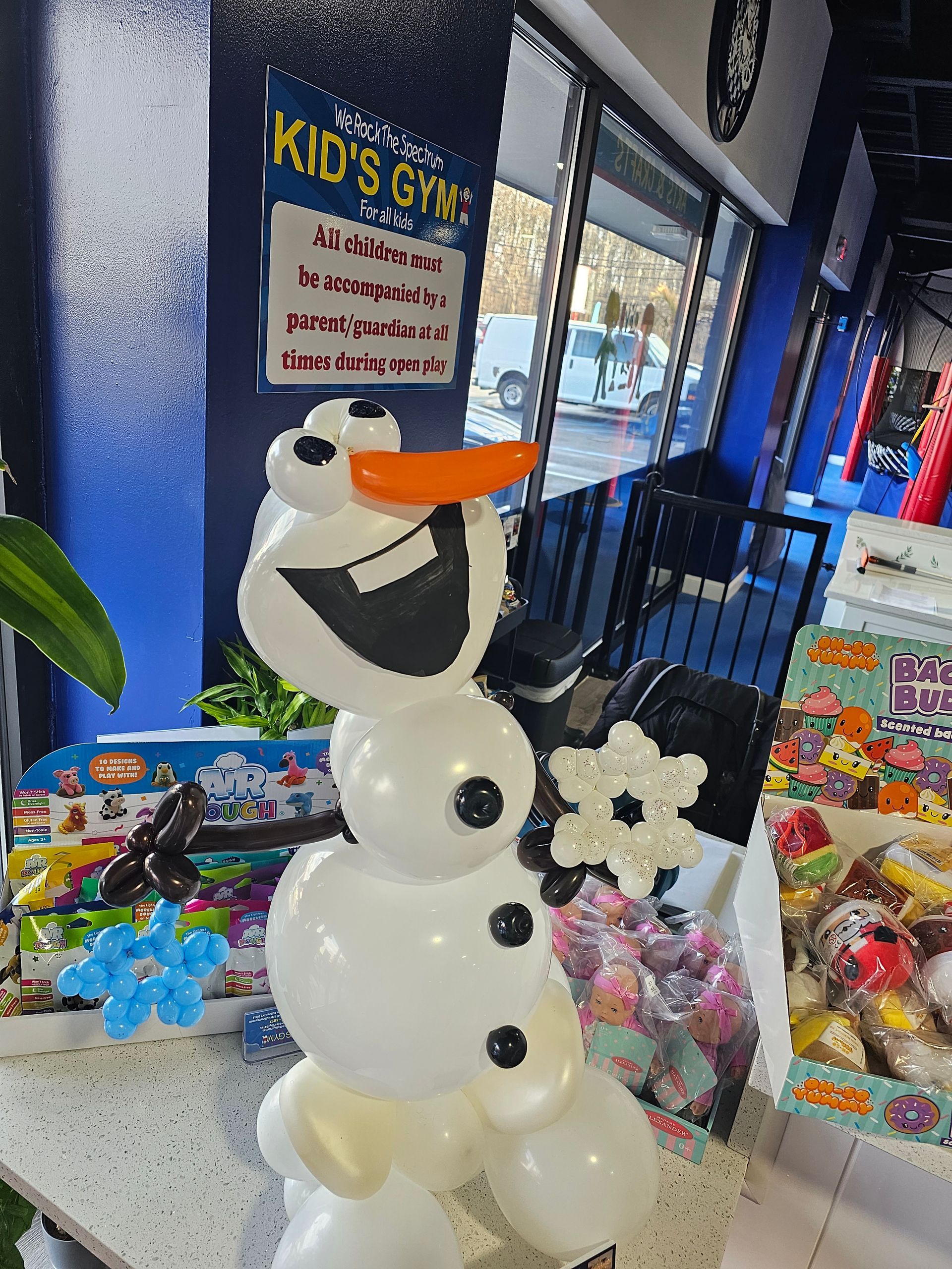 Balloon sculpture of Olaf the snowman at Kid's Gym, with black buttons and an orange nose.