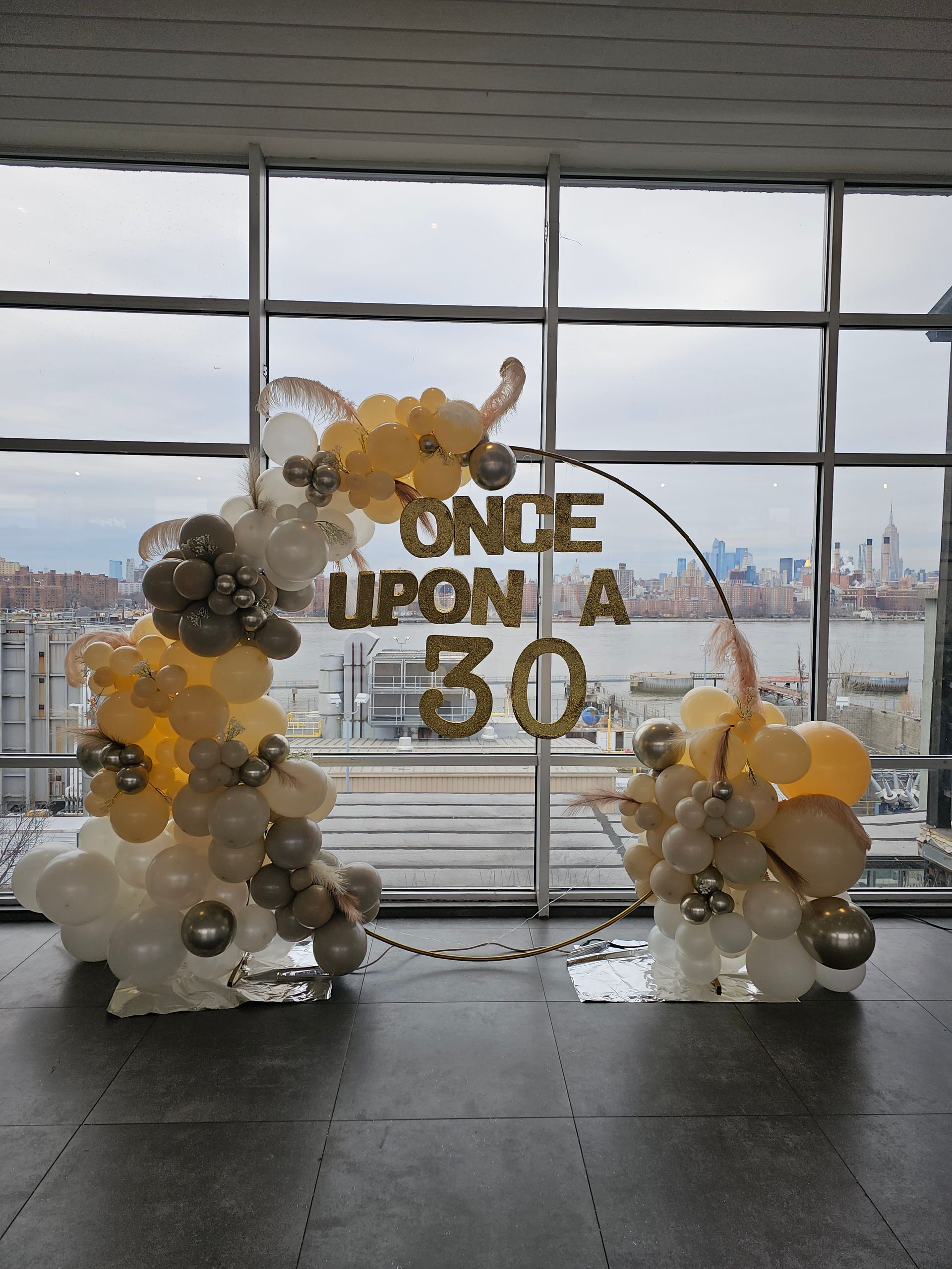 Balloon arch for a 30th birthday, with gold and white balloons and text 