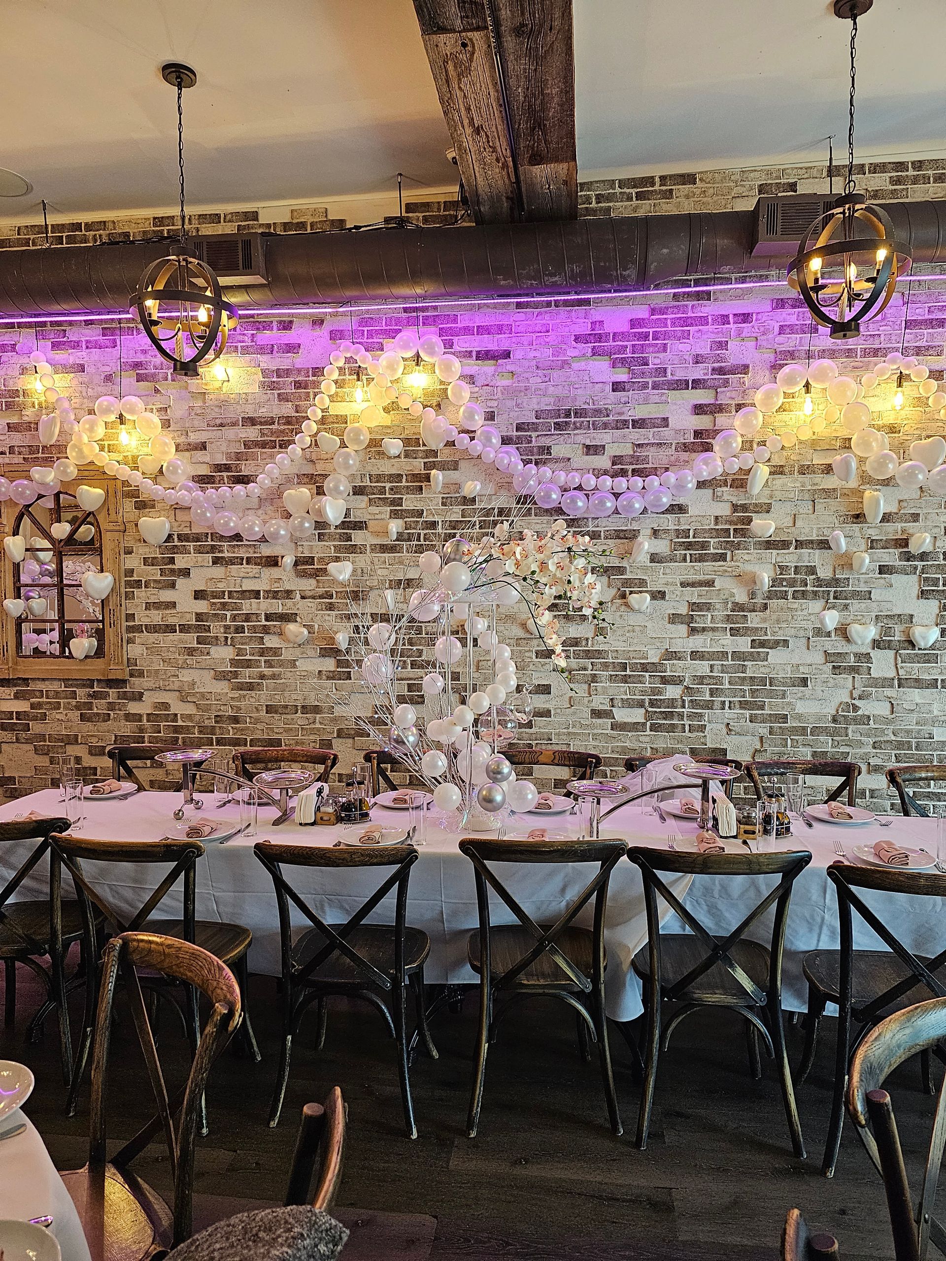 Formal dining table set in a room with a brick wall and decorative lights.