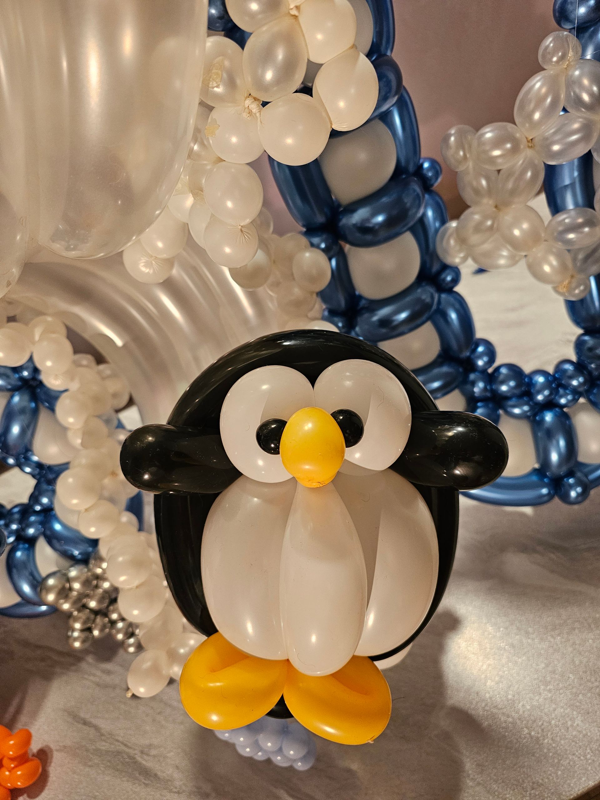 Balloon penguin decoration with white, black, and yellow balloons.
