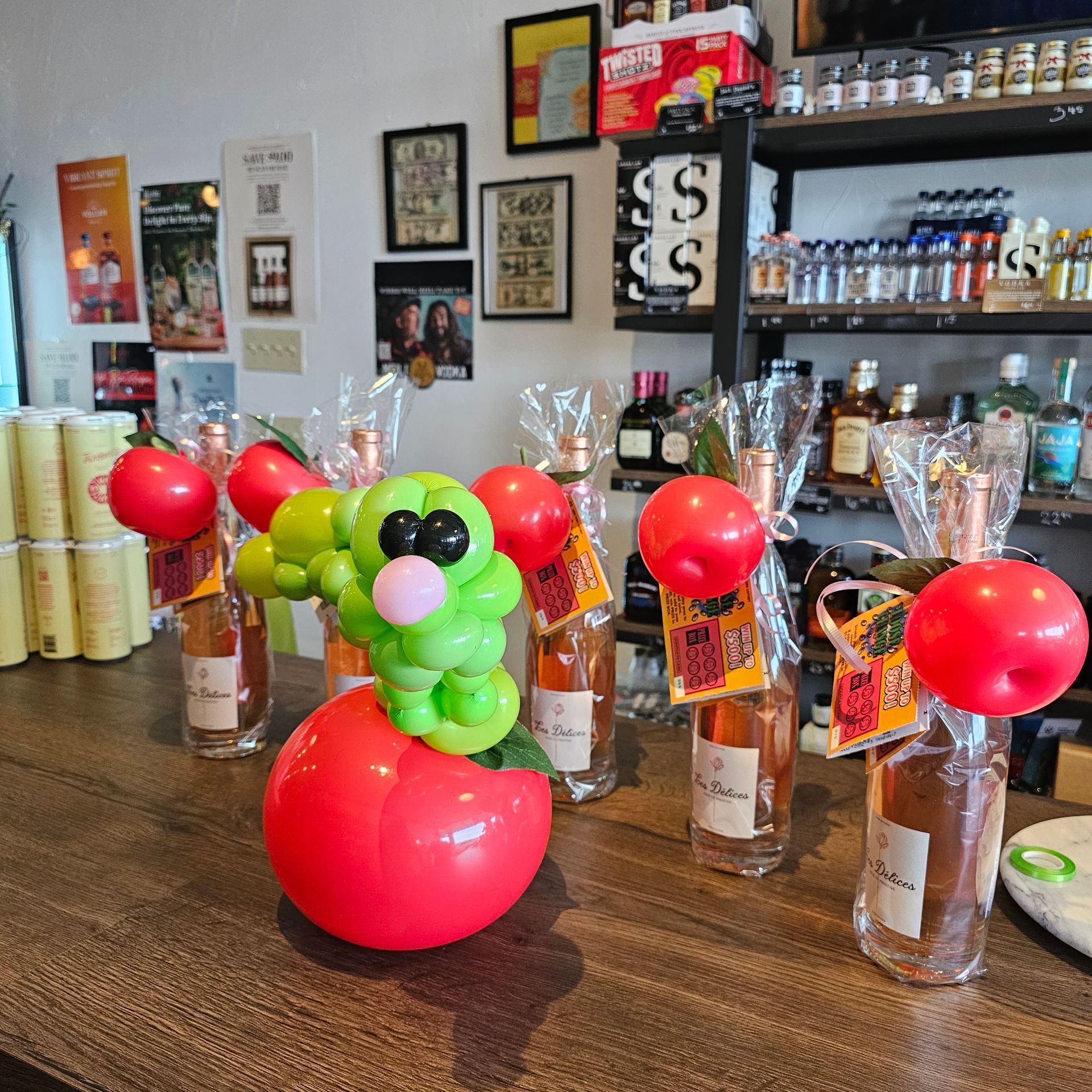 Bottles of wine decorated with balloons on a wooden counter in a store.