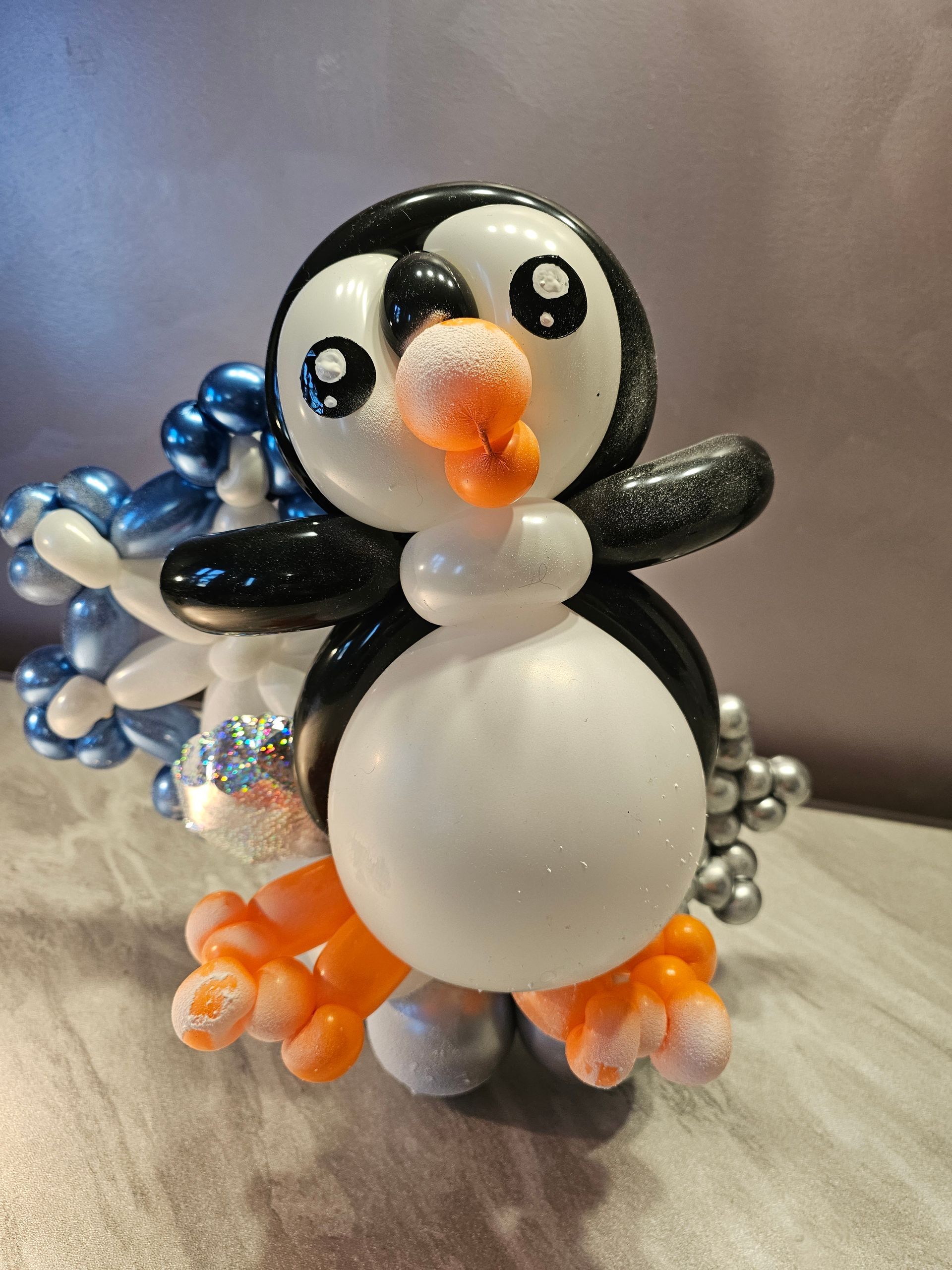 Balloon penguin sculpture with white belly, black head, and orange feet.