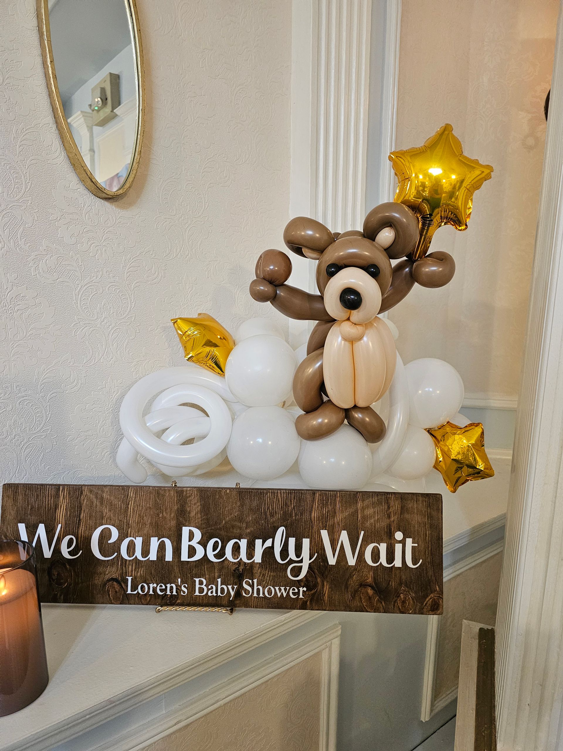 Baby shower decor with a balloon bear on a cloud, gold stars, and a 