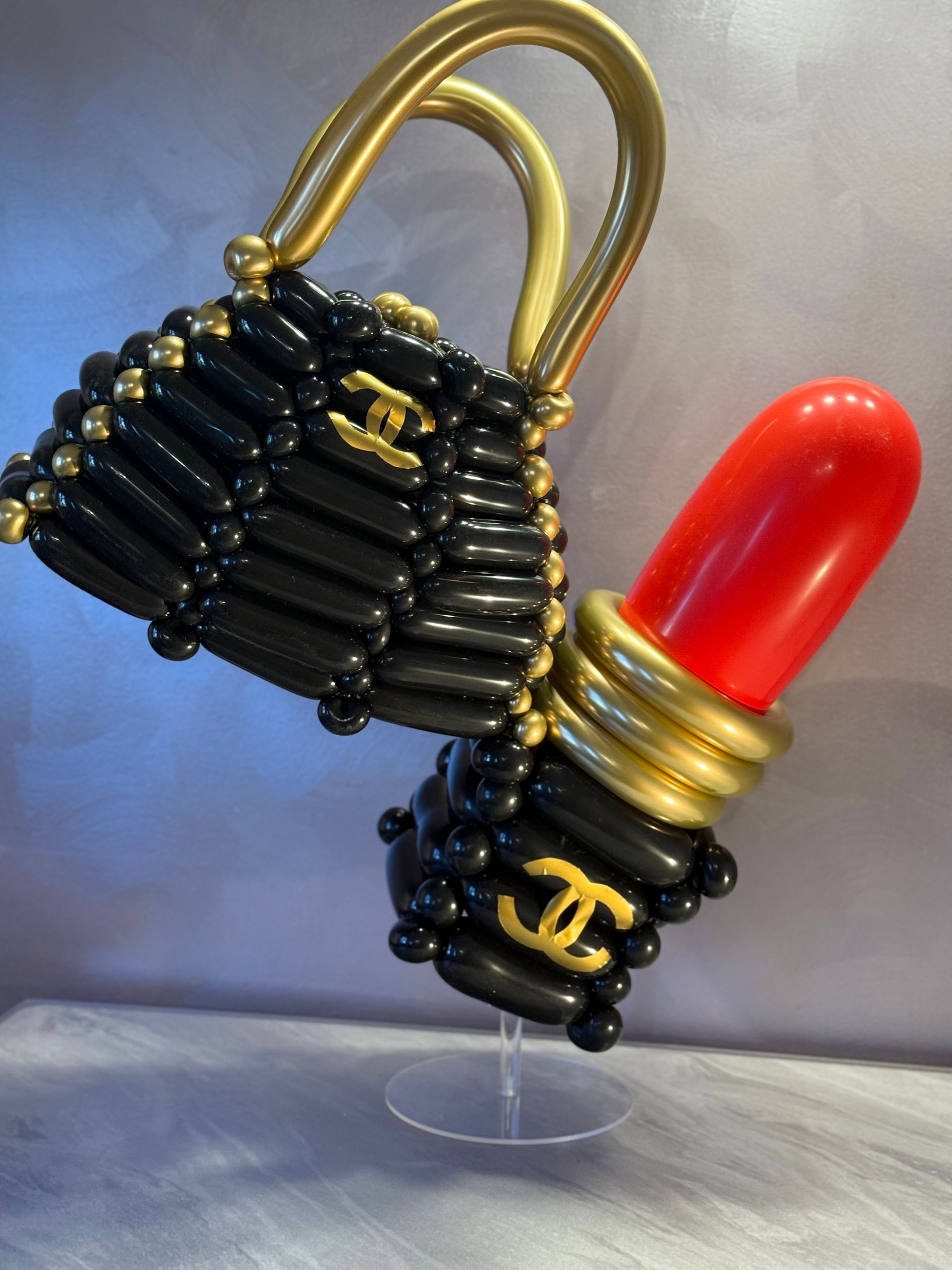 Black balloon purse and lipstick sculptures with gold accents.