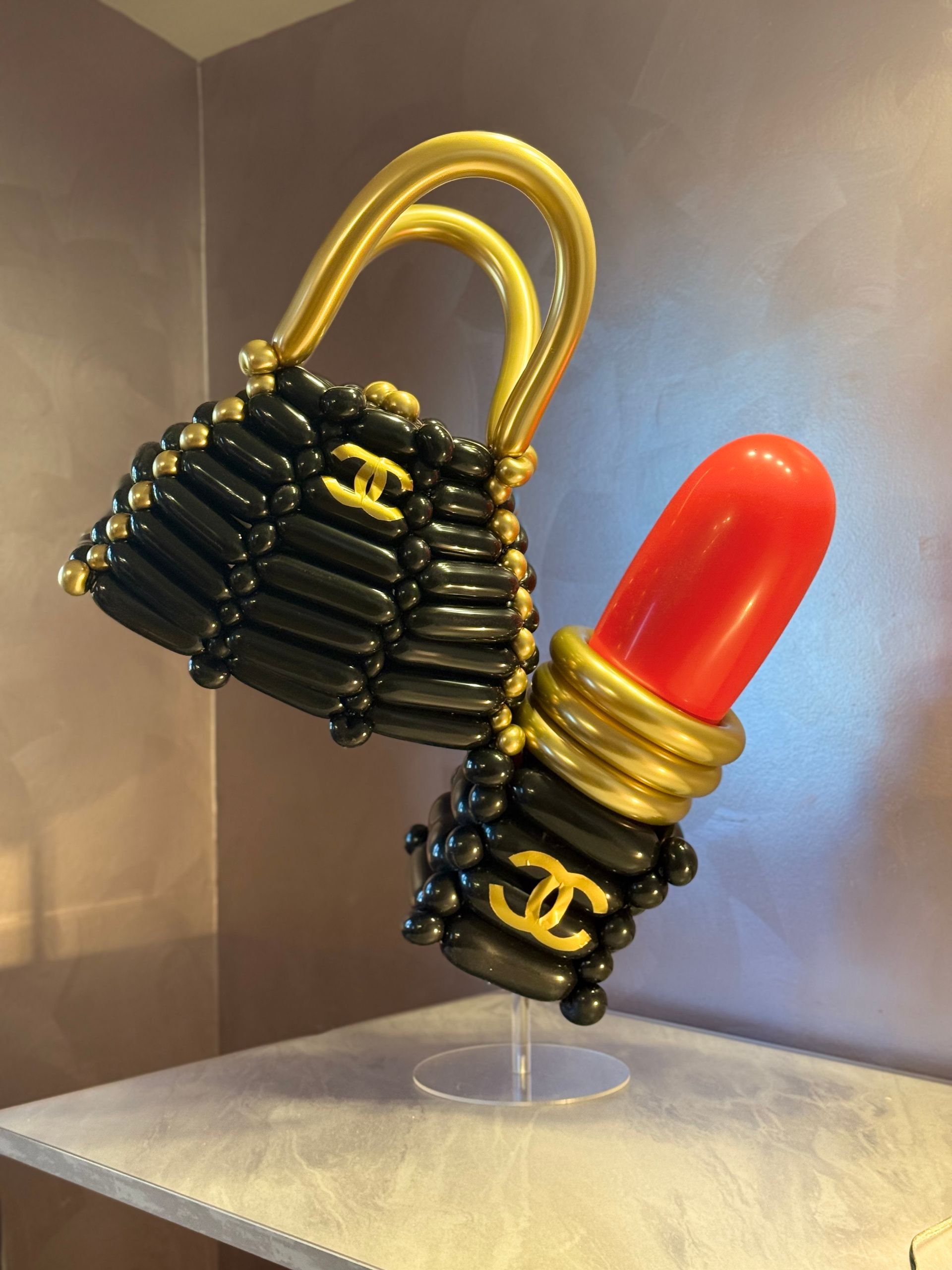 Black balloon purse and red lipstick sculpture with gold accents and Chanel logos.