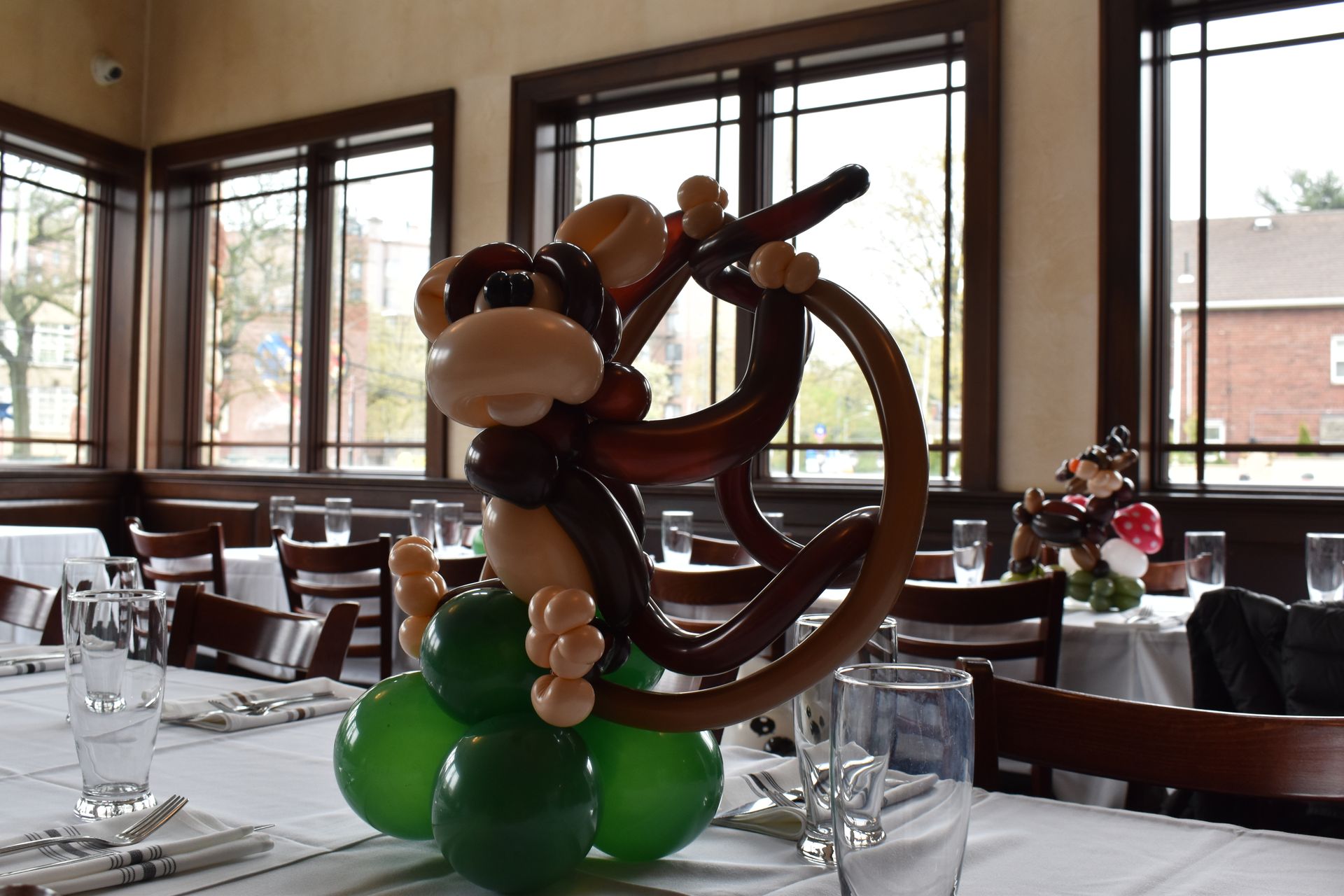 Balloon monkey centerpiece on a table with green balloons, in a dining room.