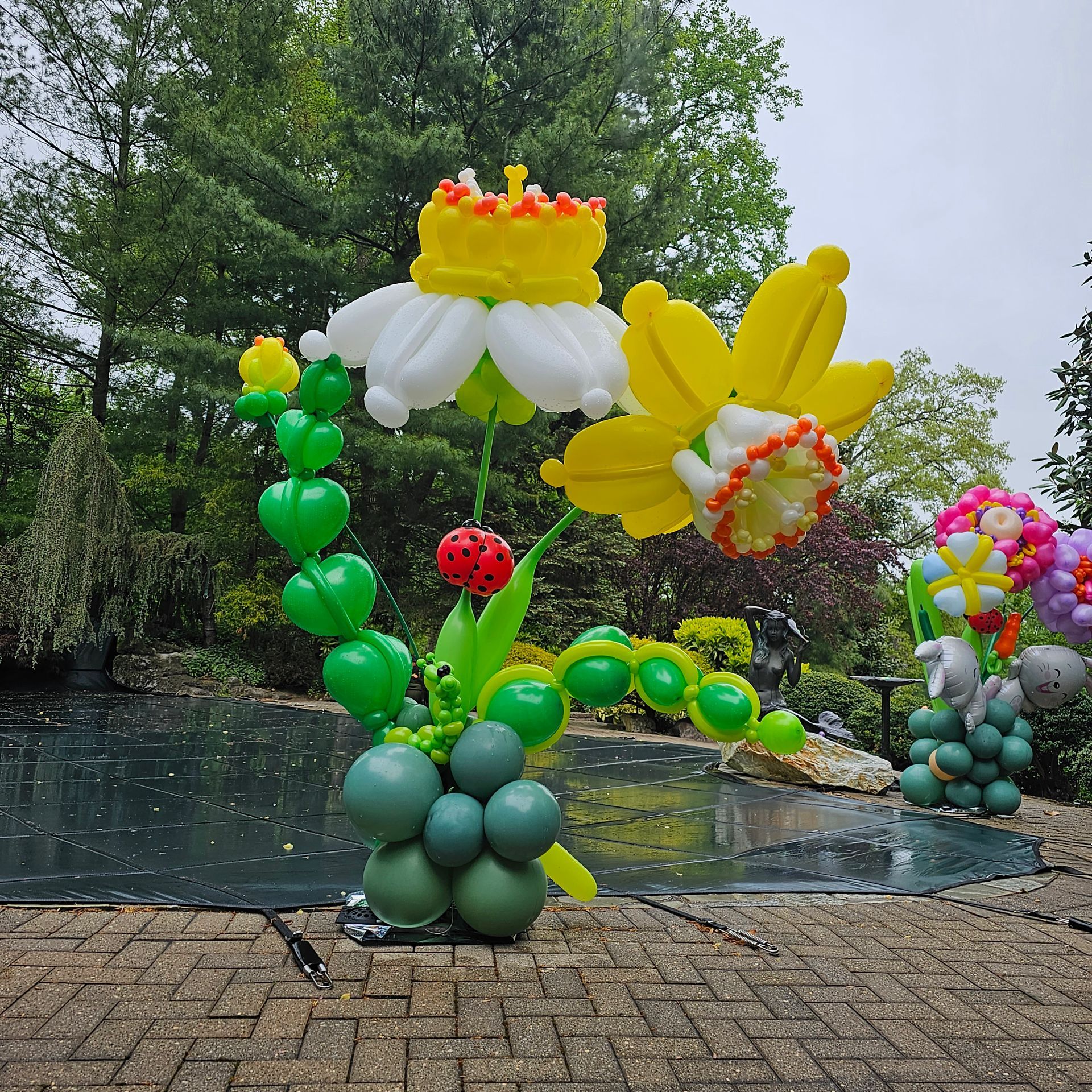 Balloon flowers near a pond. Daffodil and other colorful balloon sculptures outdoors.