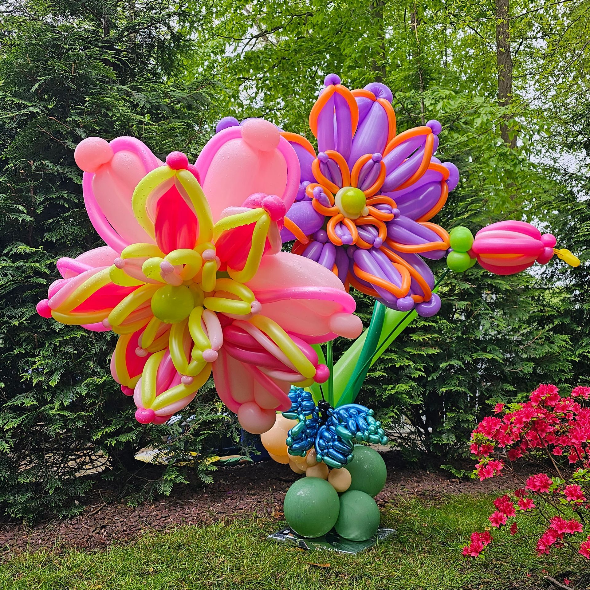 A colorful balloon flower arrangement displayed outdoors, with pink, purple, and yellow petals.