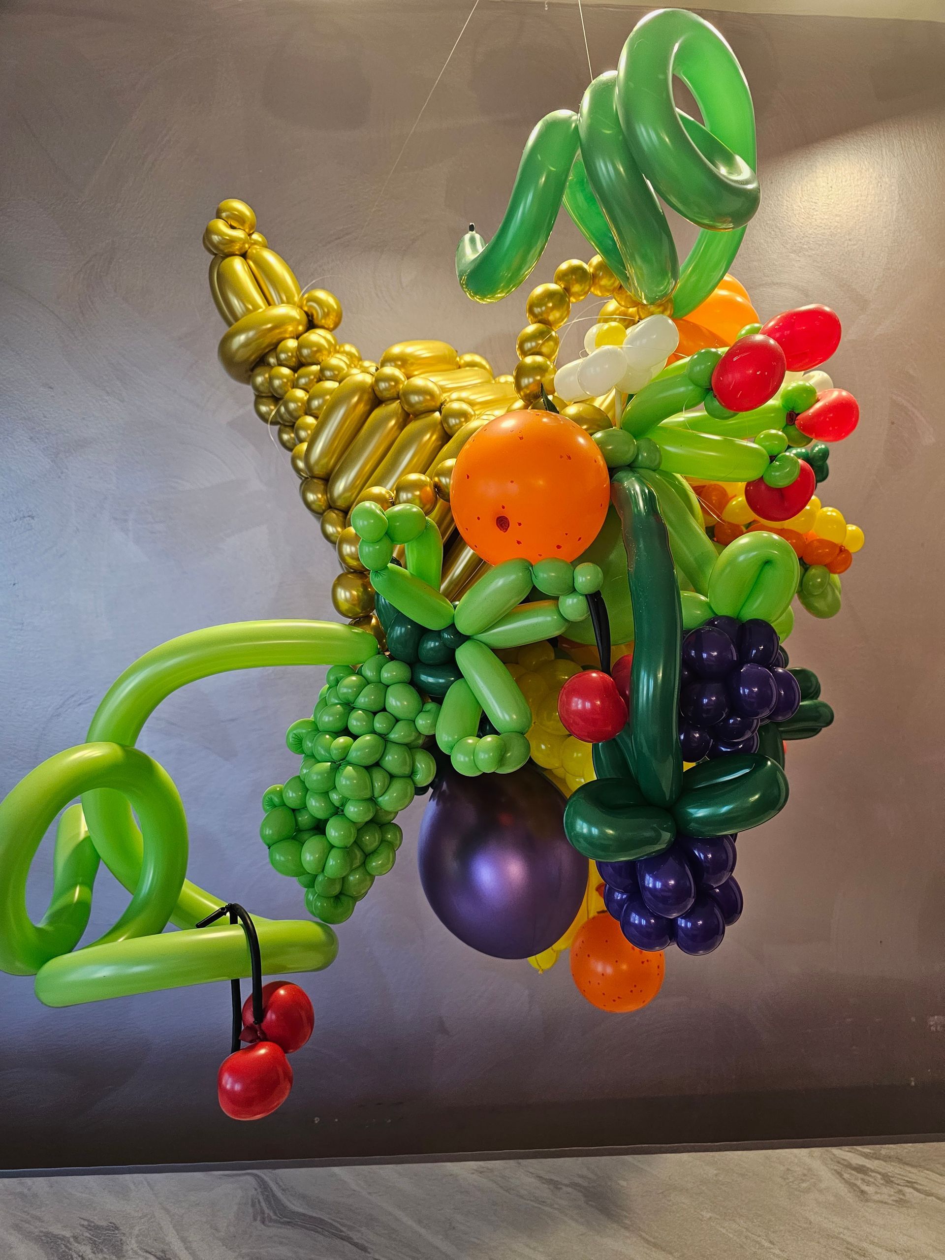 Balloon sculpture of a cornucopia filled with various colorful fruits.
