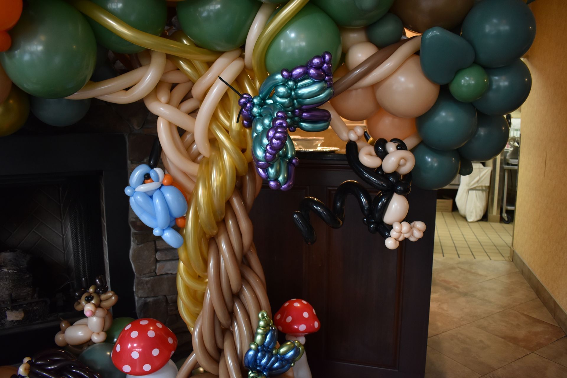 Balloon tree sculpture with bluebird, monkey, mushrooms, and butterfly.