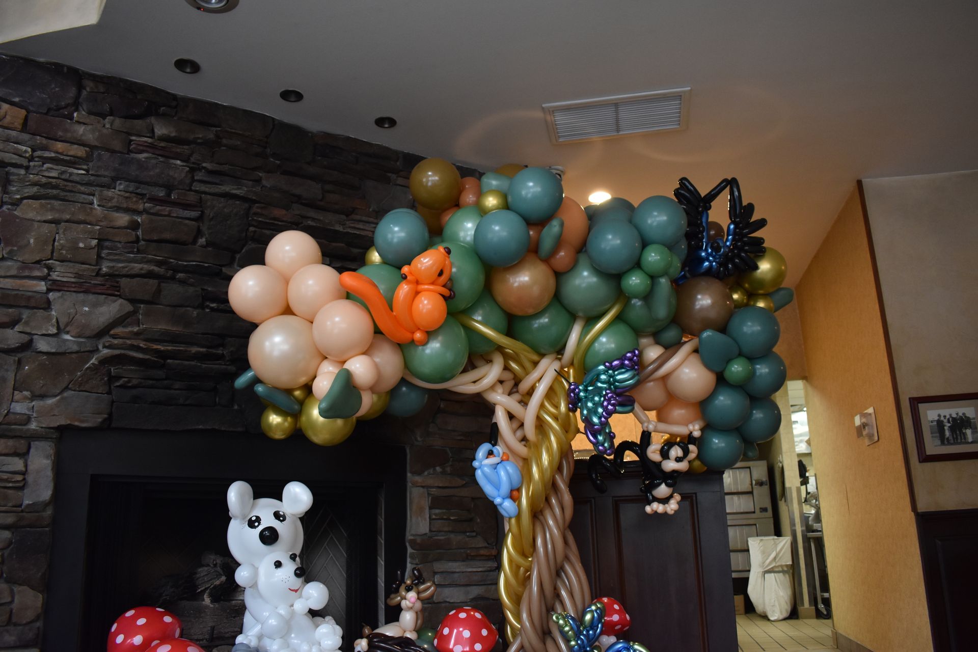 Balloon tree with squirrel and butterflies; a dog balloon, mushrooms, and a fireplace in the background.