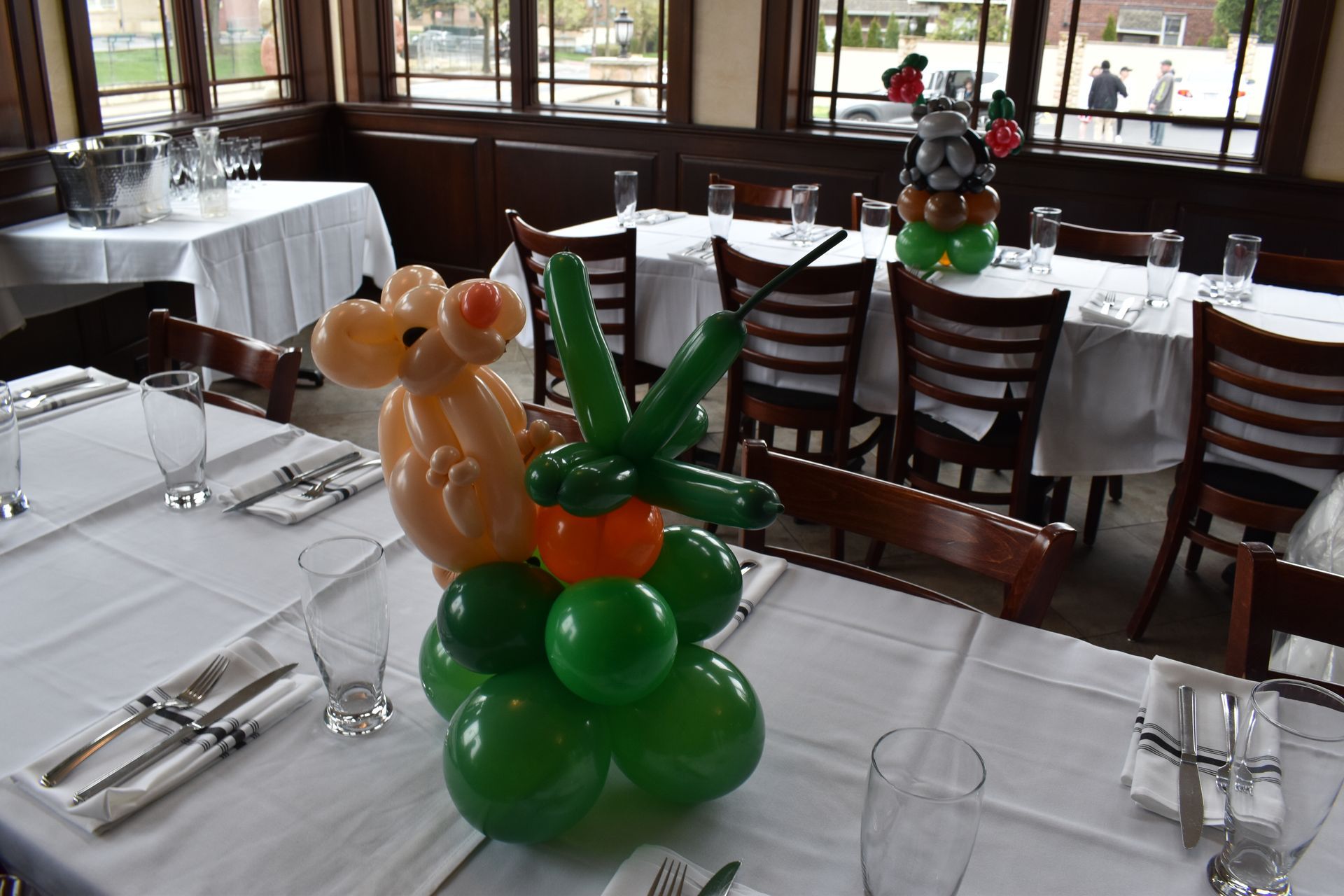 Restaurant table set with white tablecloth, balloon animal centerpiece.