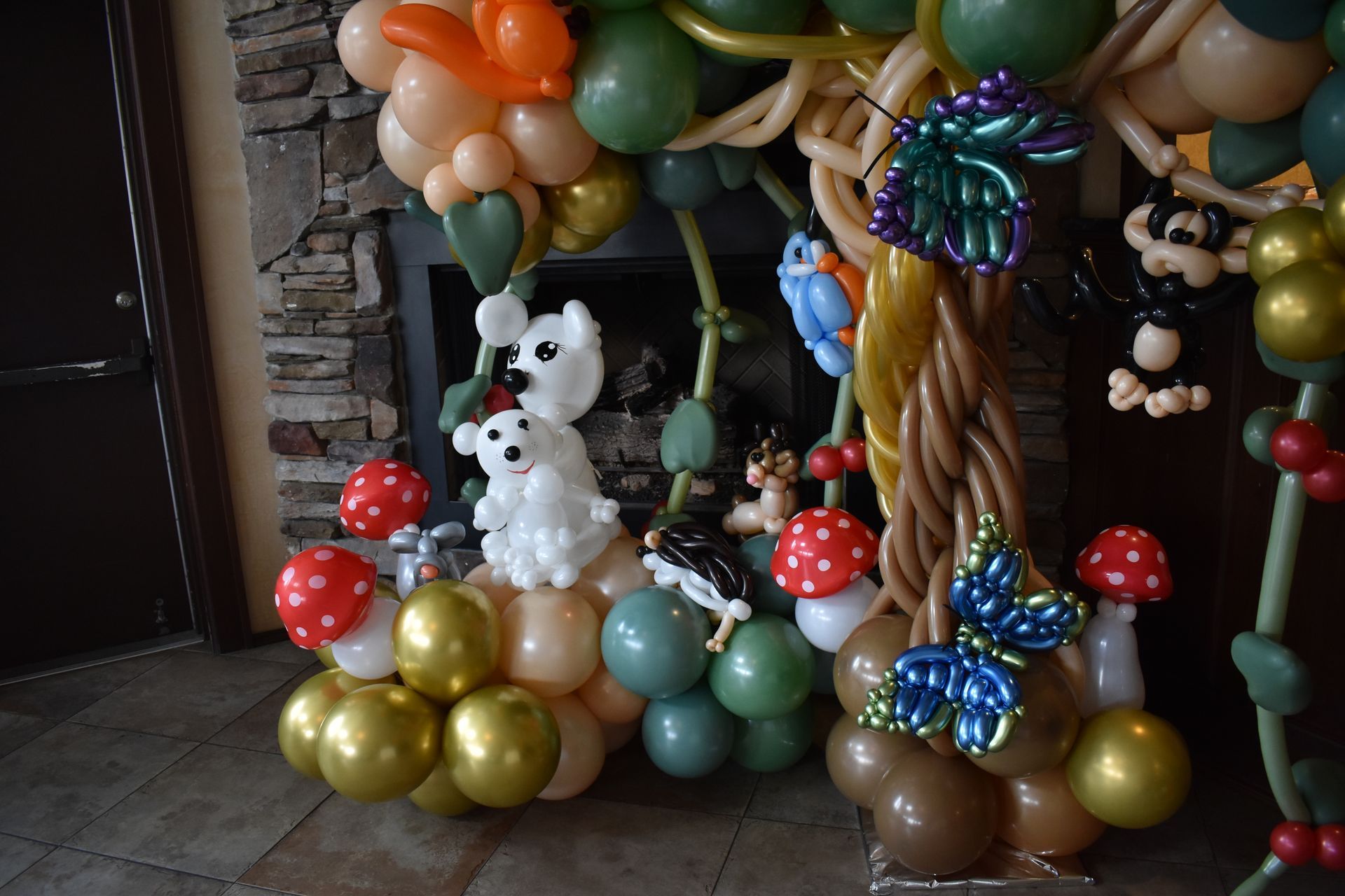 Balloon animal forest scene with bears, mushrooms, and a tree, next to a fireplace.
