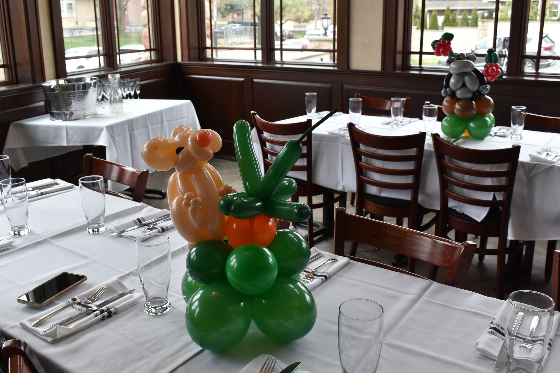 Restaurant dining room with tables set for a meal, decorated with balloon sculptures.