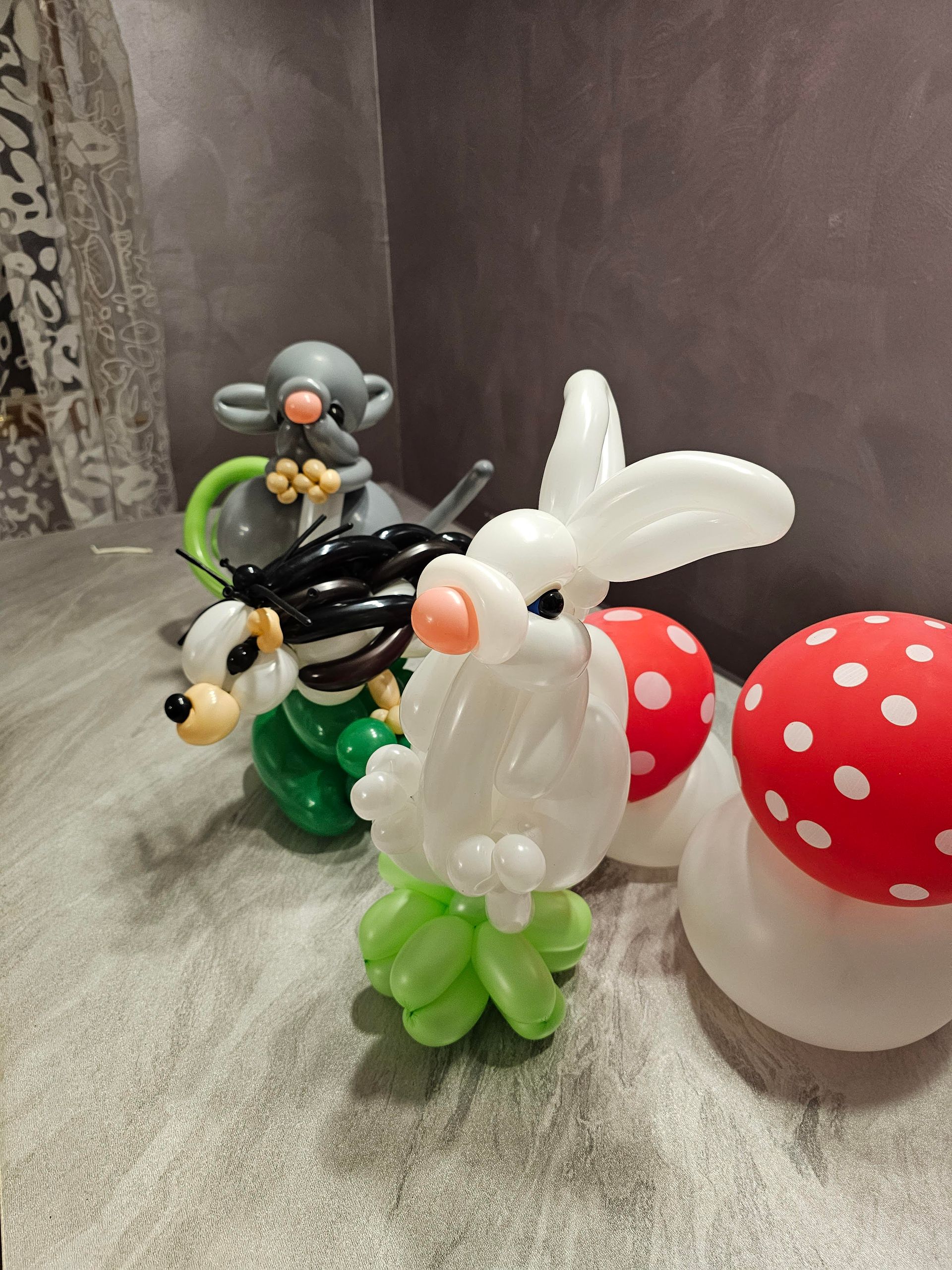 Balloon animals: rabbit, mouse, hedgehog, and toadstools. White, green, black, red, and gray balloons.
