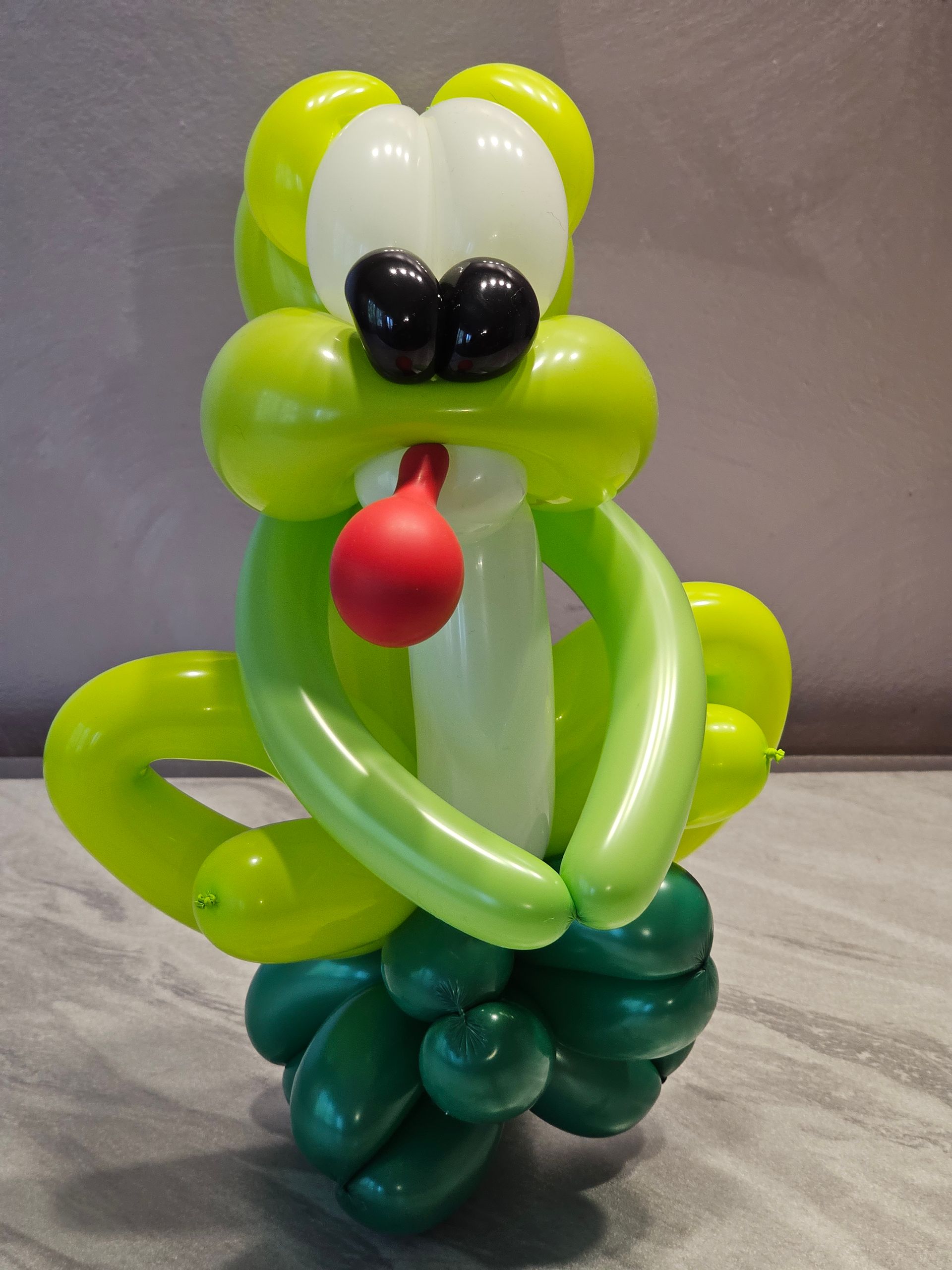 Green and white balloon dog sculpture with red tongue and black nose.