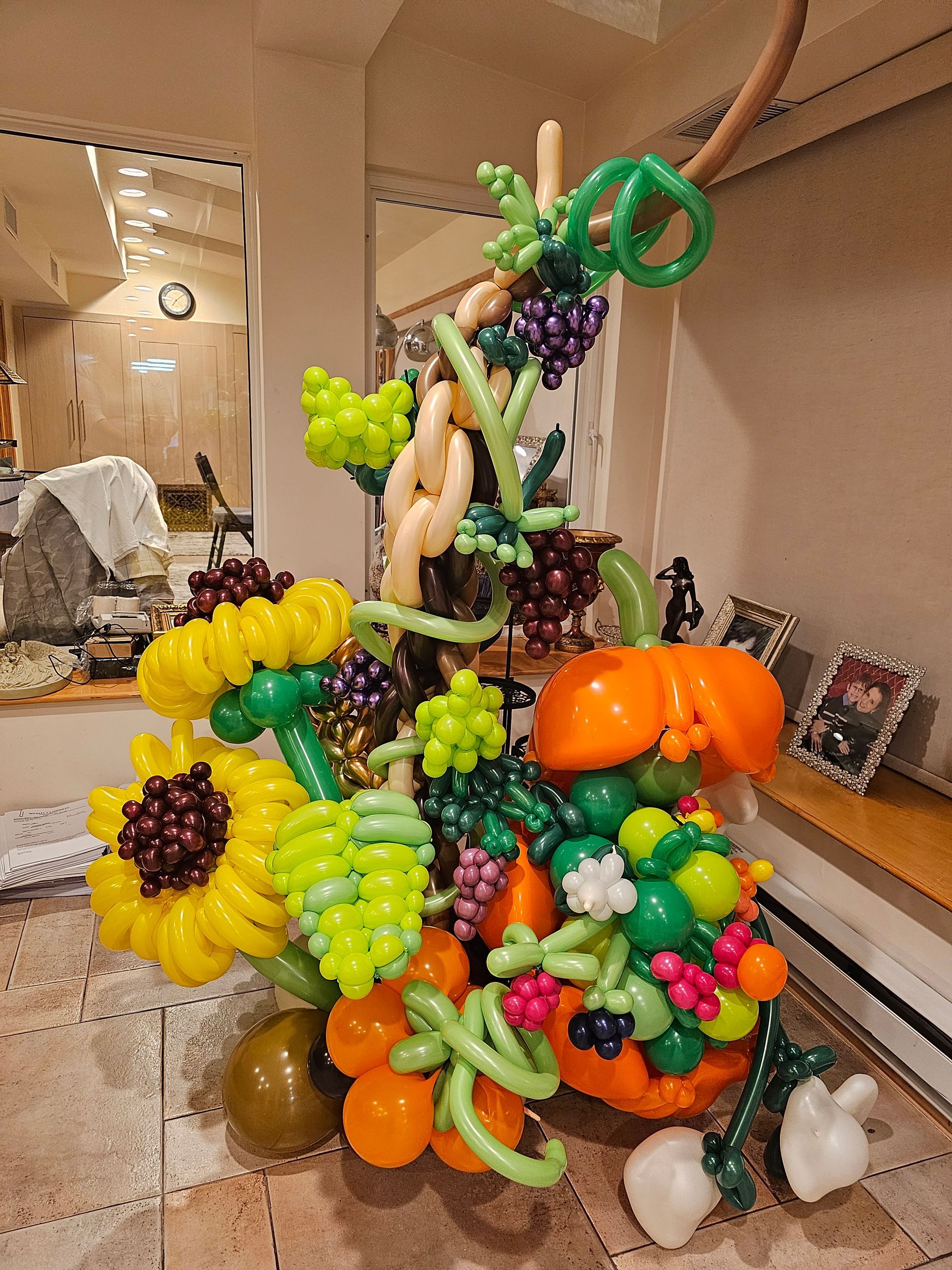 Colorful balloon sculpture of a harvest scene, including sunflowers, grapes, pumpkins, and a decorative vine.