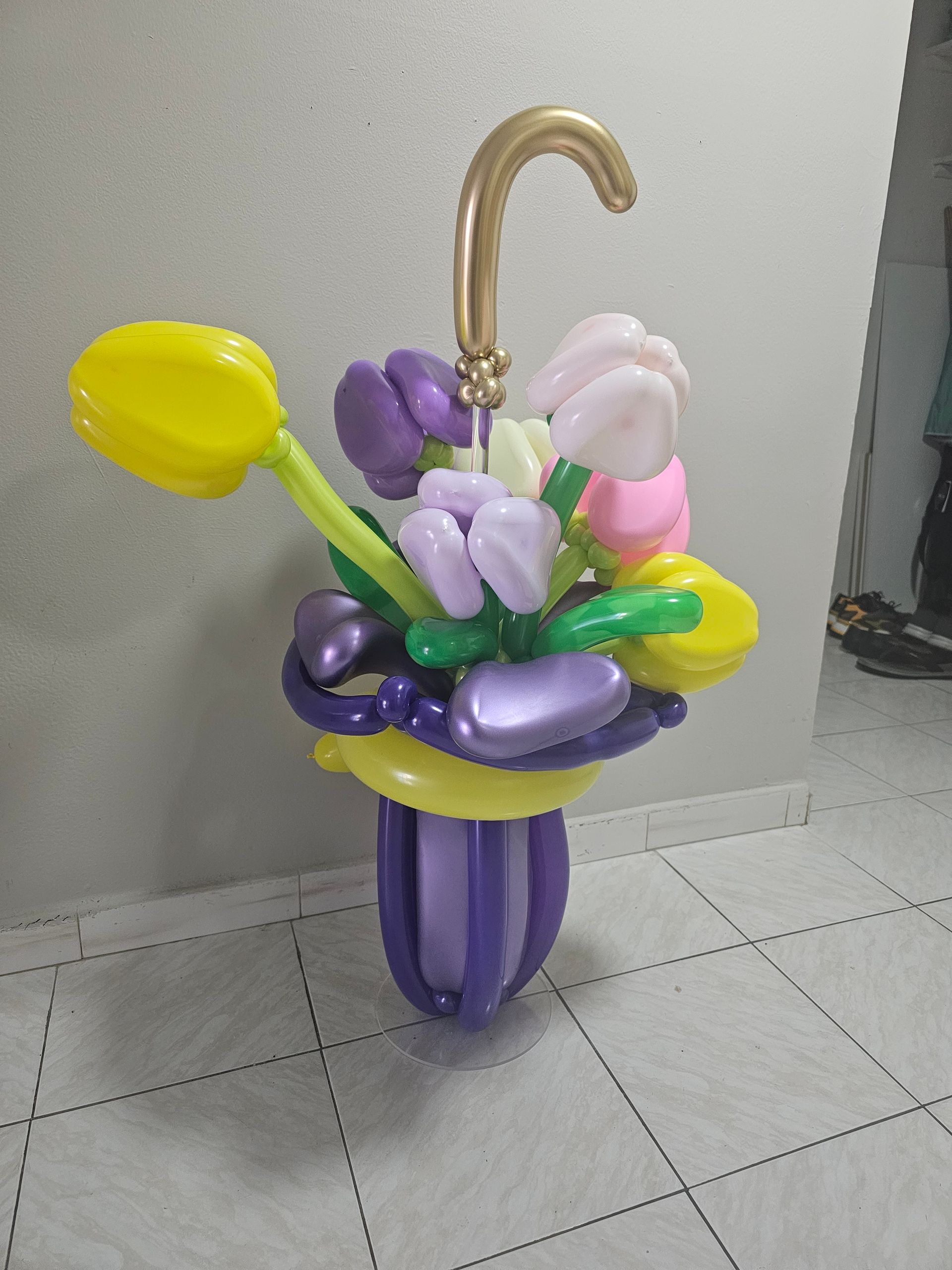 Balloon sculpture of a purple umbrella with a bouquet of colorful tulip balloons.