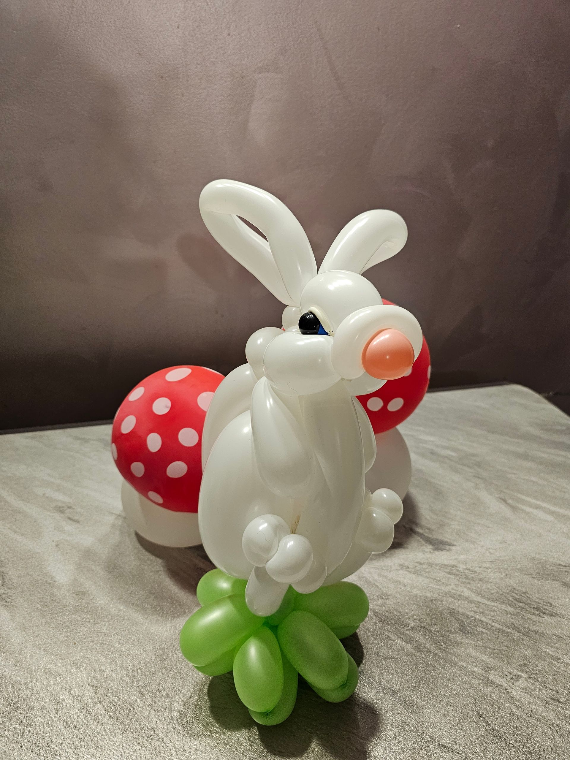 White balloon bunny with red and white polka dot balloon mushroom. Green balloon base.