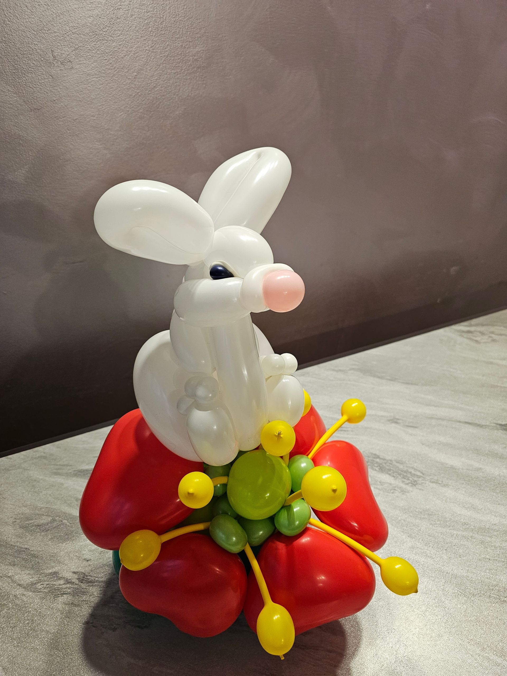 White balloon rabbit atop a red balloon flower with green and yellow accents.