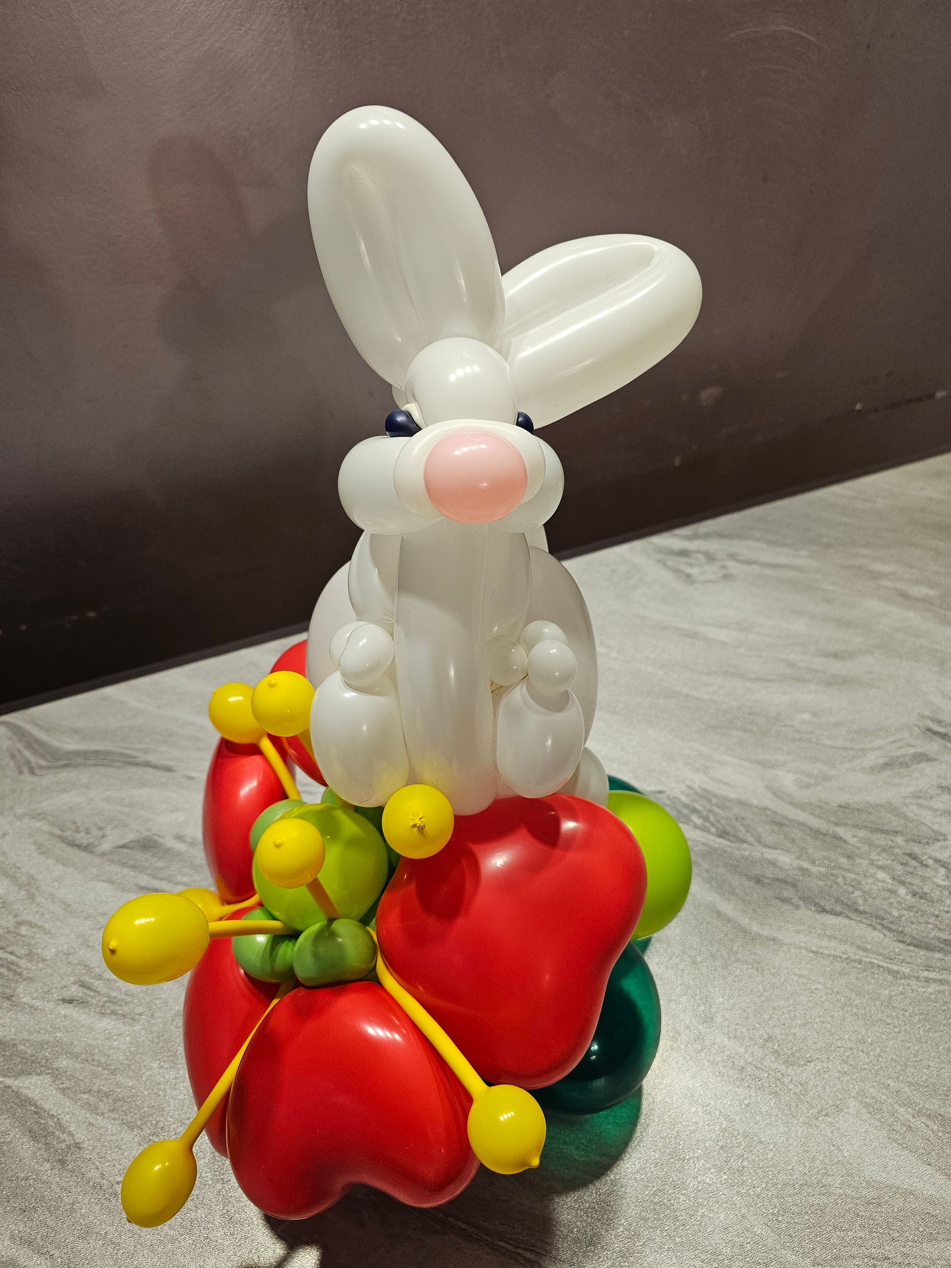 White balloon bunny on a balloon base of red peppers and greenery; neutral background.