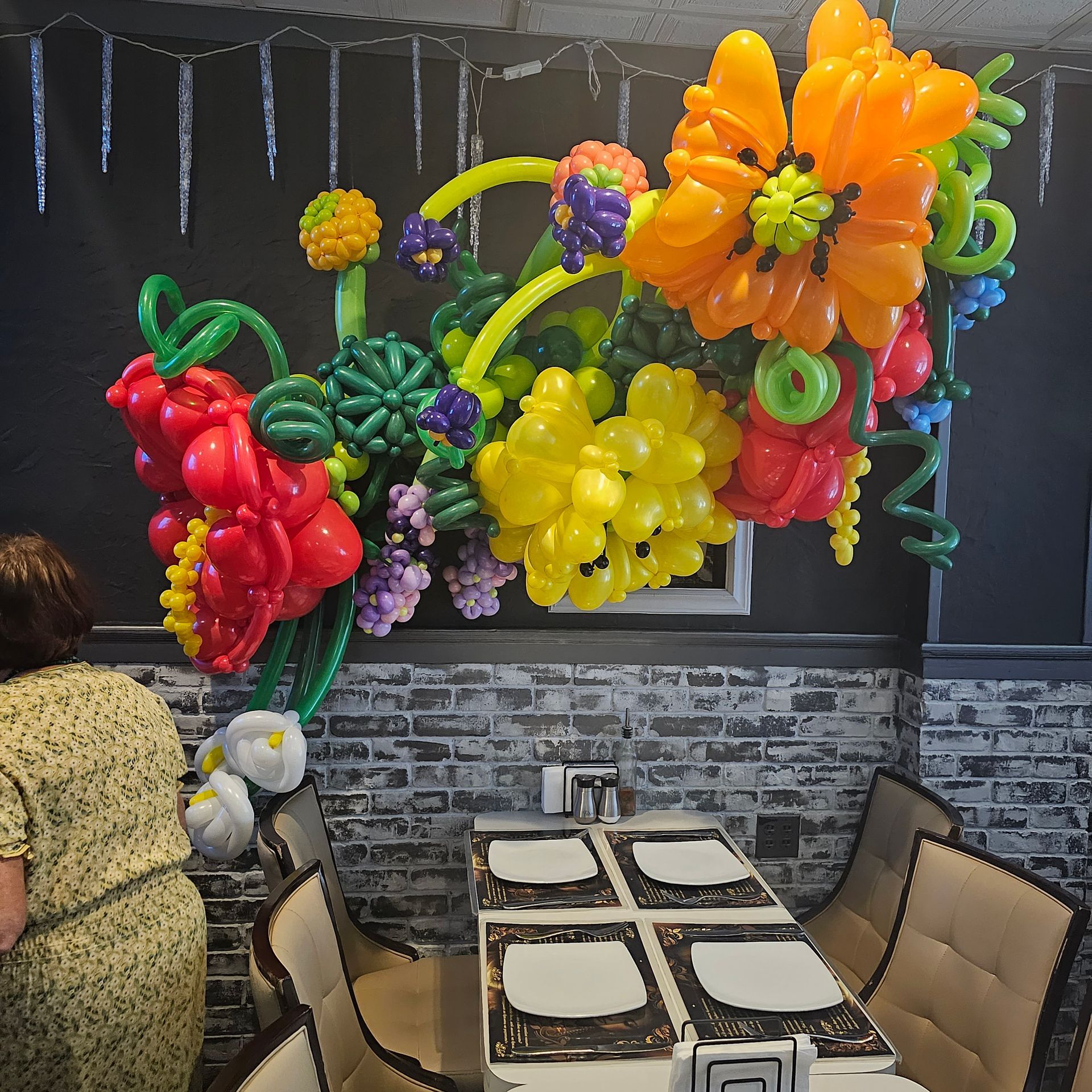 Balloon flower arrangement above a dining table with a person in a floral dress.