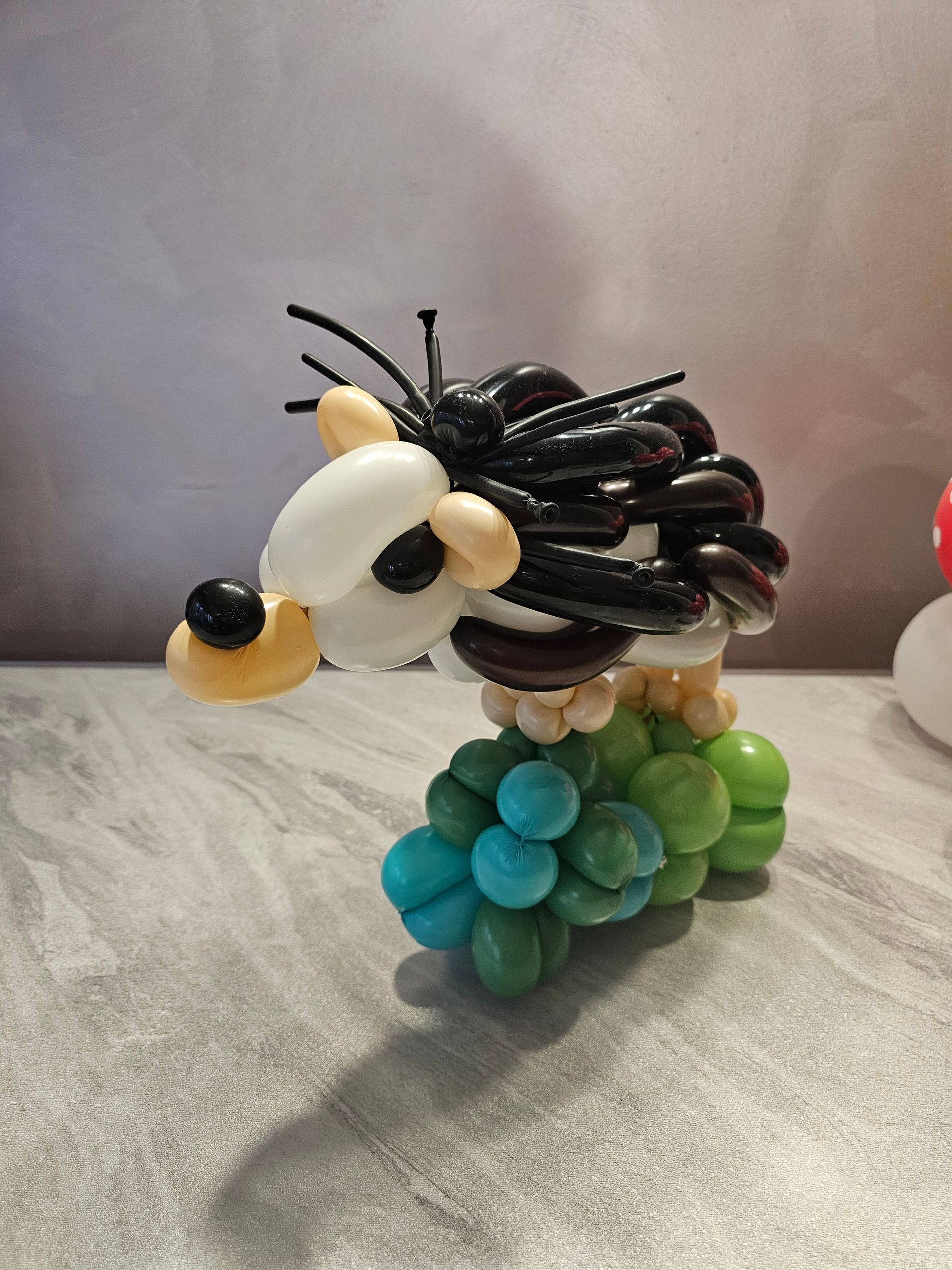 Balloon sculpture of a hedgehog with black and white quills, standing on green and blue balloons.