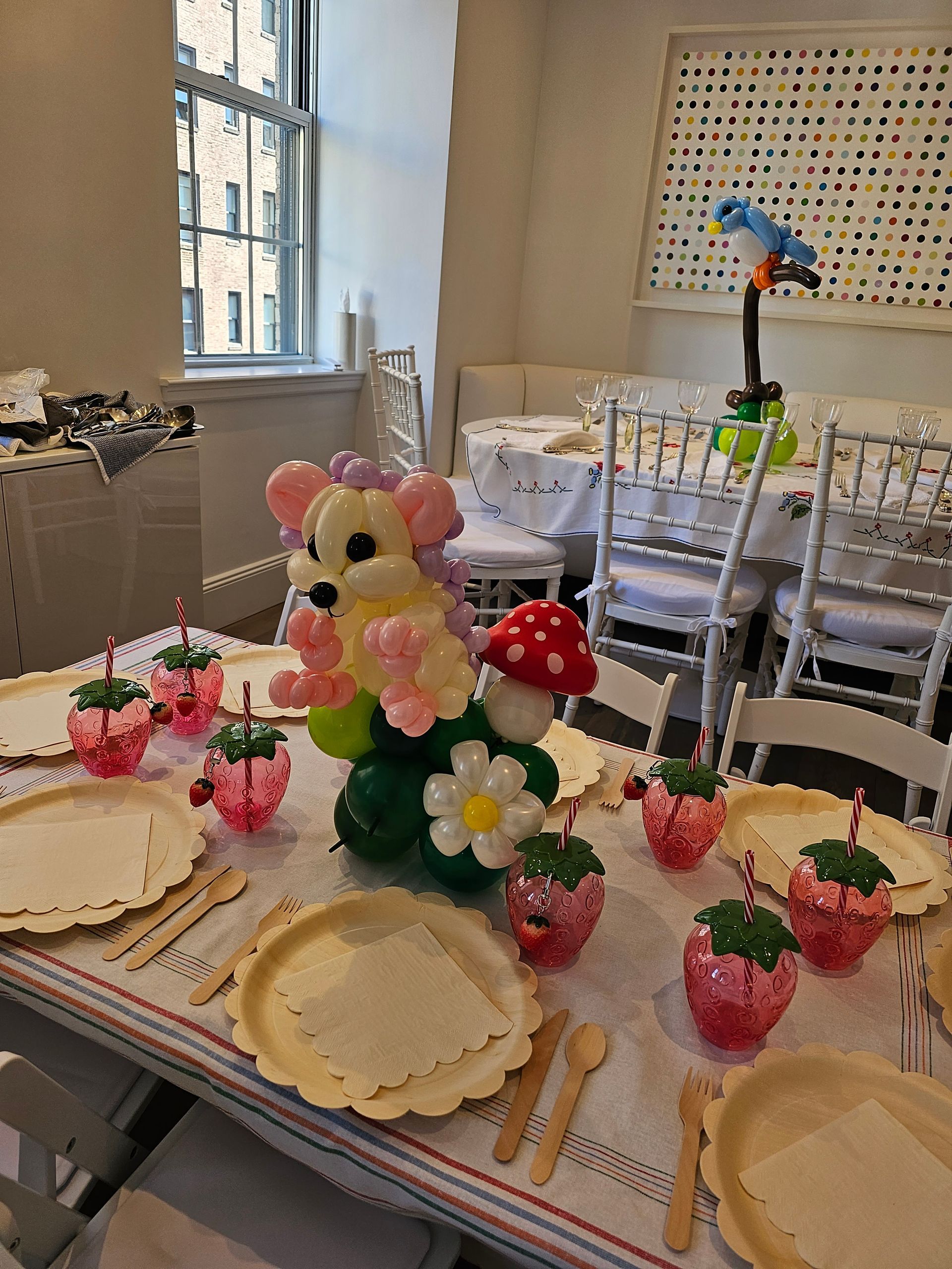 Table setting with balloon dog and strawberry-themed decorations.