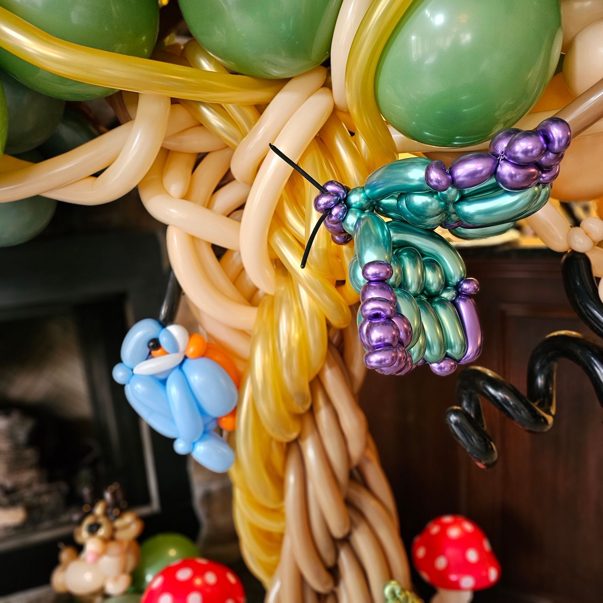 Balloon tree sculpture with bird, butterfly, and mushrooms.