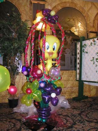 Tweety Bird balloon sculpture in a balloon flower basket, bright colors, festive setting.