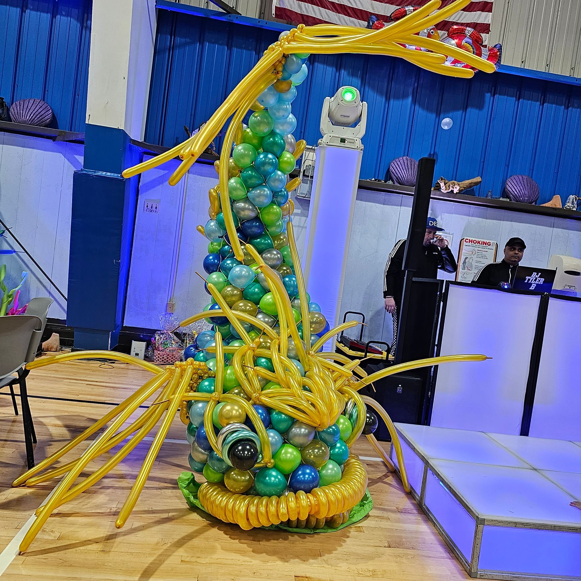 Balloon sculpture resembling a sea creature with yellow and blue balloons, party setting.