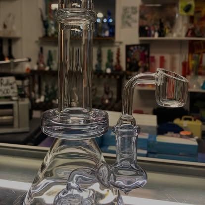 Clear glass dab rig with a curved banger, set in a store.