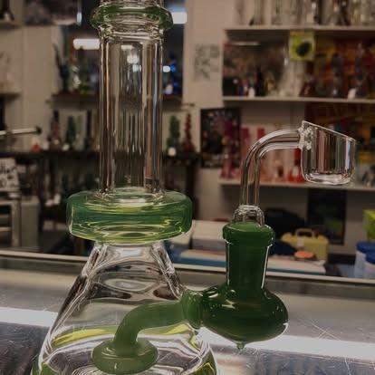 Green glass bong with quartz banger, in a smoke shop.