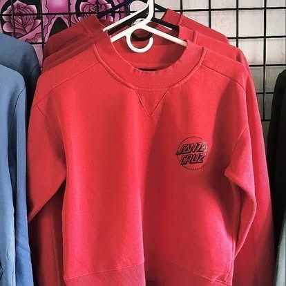 Red Santa Cruz sweatshirt with logo on hanger, displayed on a clothing rack.