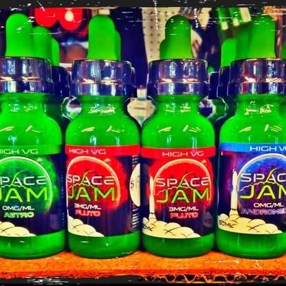 Bottles of Space Jam e-liquid: green bottles with colorful labels, various flavors and nicotine strengths.