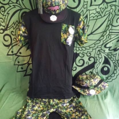 Black shirt with camo sleeves, camo shorts, a hat, and a ball cap on a green backdrop.