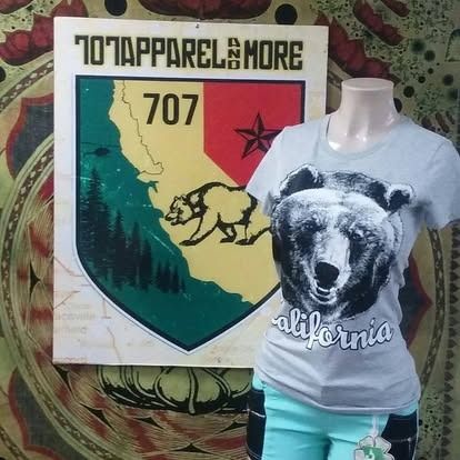 Mannequin wearing a gray bear graphic tee and blue shorts, next to a sign with California map design.