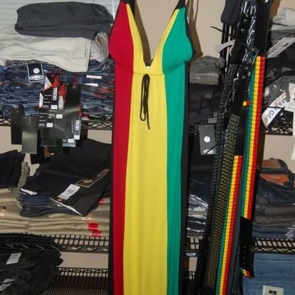 A long dress in red, yellow, and green, hanging among clothing on shelves.