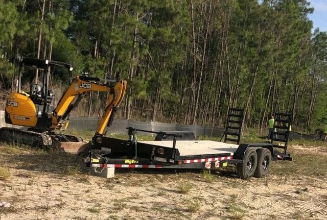 Small Excavator Next to a Trailer in a Field — Cape Coral, FL — Channel Mark Shell 