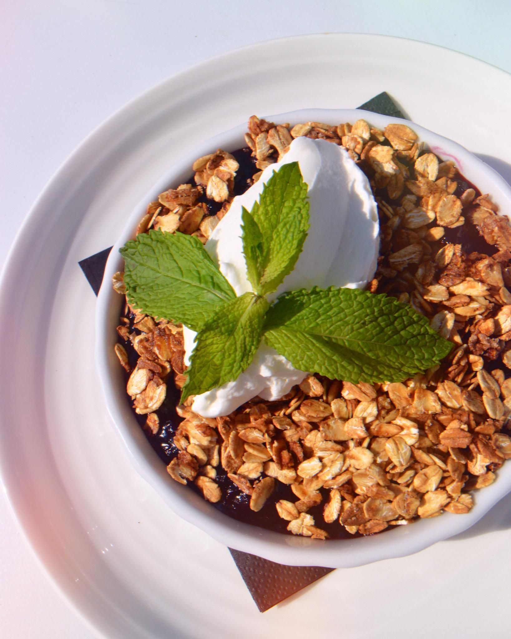 A bowl of granola with whipped cream and mint leaves
