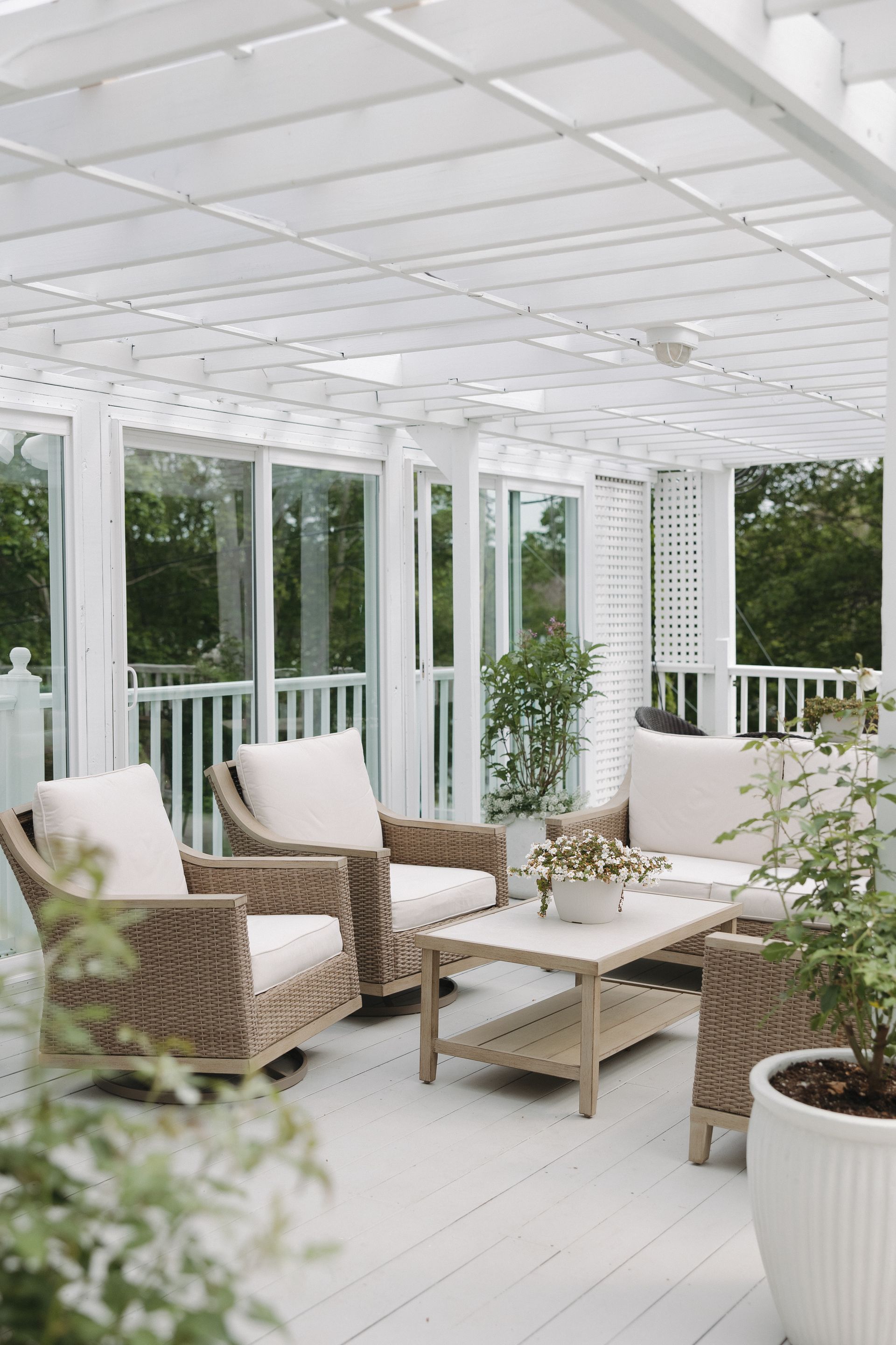 A porch with rocking chairs and tables with a view of the ocean.
